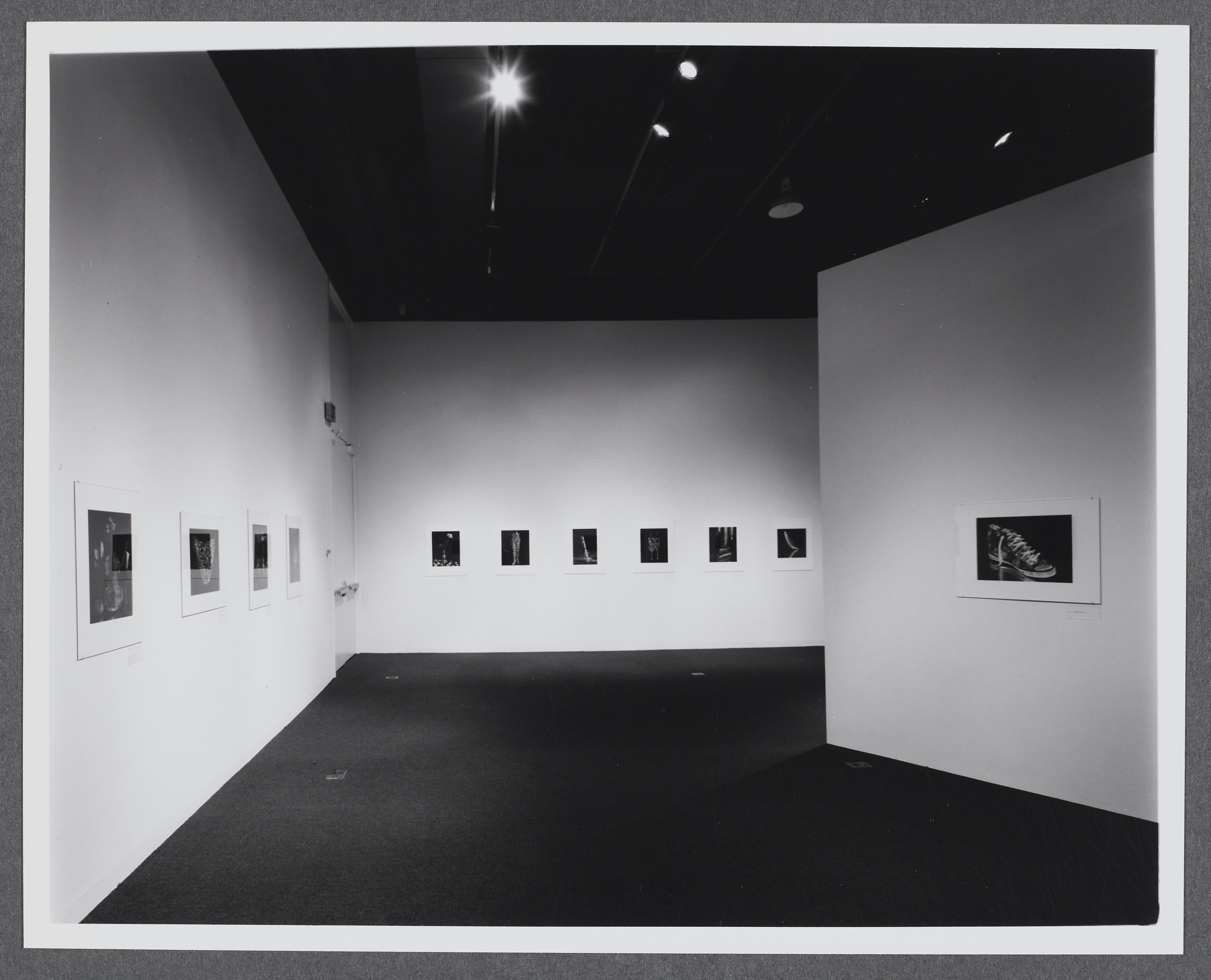 Black and white photographs line the gallery walls. They are all displayed in a row at the same height.