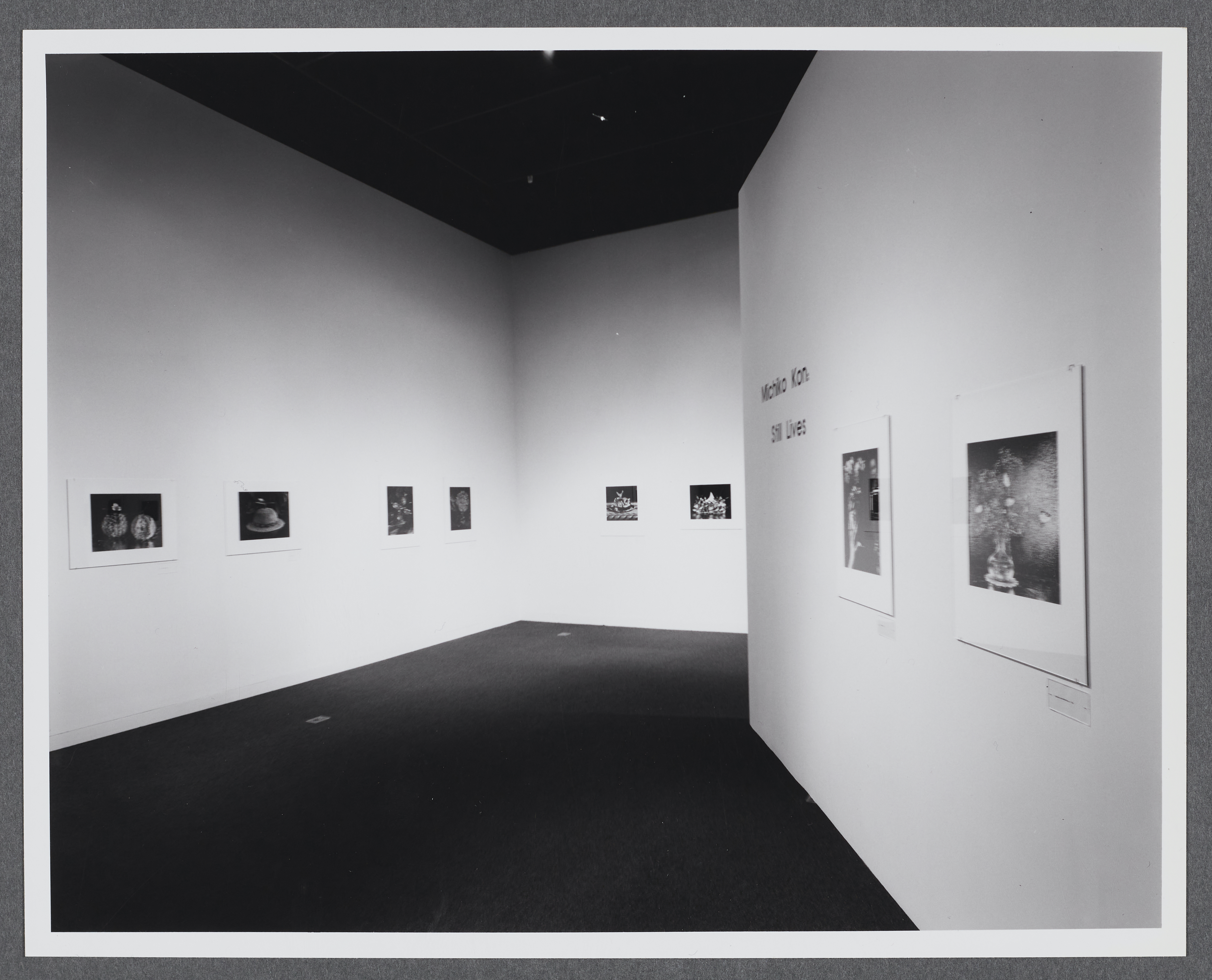 Black and white photographs line the gallery walls. They are all displayed in a row at the same height.