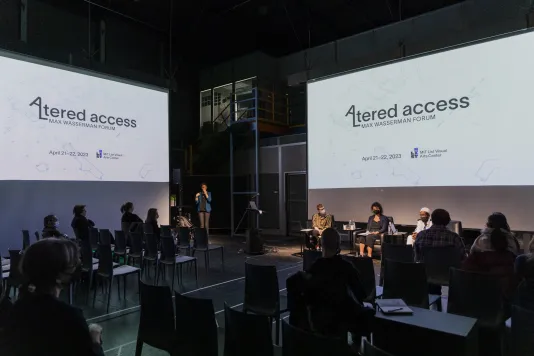 An audience sits in a dark room lit by two projectors on the left and right. The screens read "Altered Access 2023 Max Wasserman Forum" with the program dates and the MIT List Visual Arts Center logo.