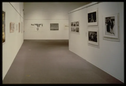 Groups of black and white photographs of varying sizes line the walls of the gallery.