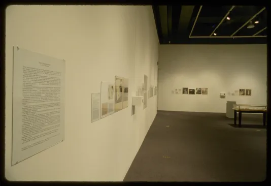 Scientific texts about flora line gallery walls, with a glass table in the middle of the room.