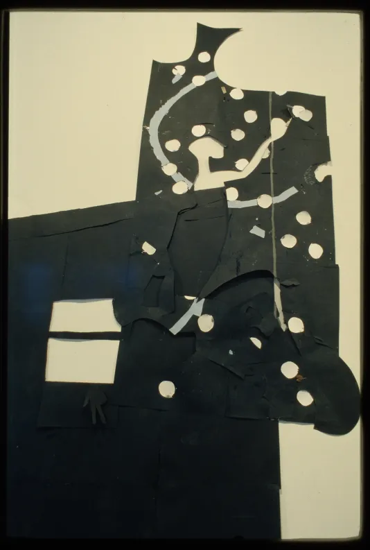 Large black paper cut out with circles and squares cut out of the middle hangs on the gallery wall.