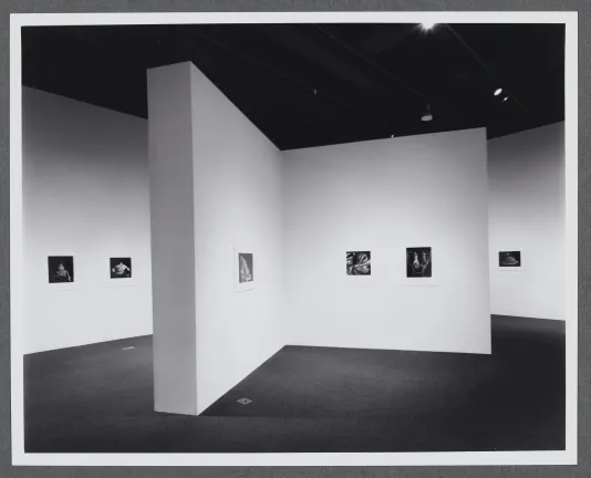 Black and white photographs line the gallery walls. Two walls join in the center of the room to display more photographs.