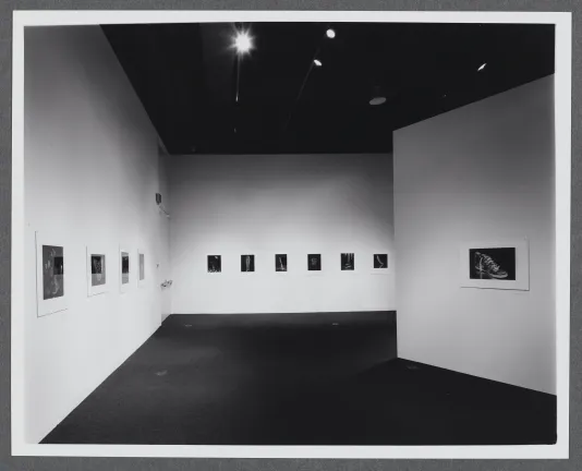 Black and white photographs line the gallery walls. They are all displayed in a row at the same height. 