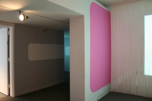 Side view of a wall with a pink rectangle with rounded edges allows viewers to observe the edges of the space.