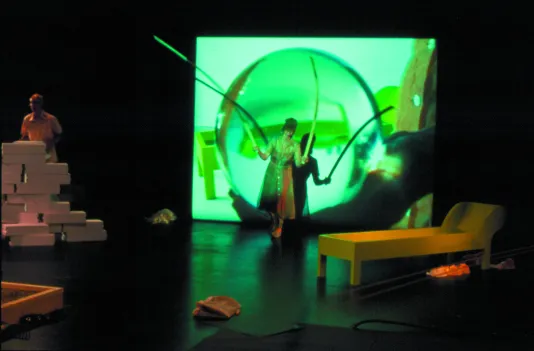Photo of the artist performing with a large green screen in the background.
