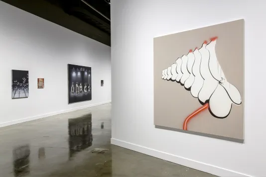 5 paintings on 2 walls, in foreground painting neon red-pink line emanates from the bottom between white legs pointed upward.