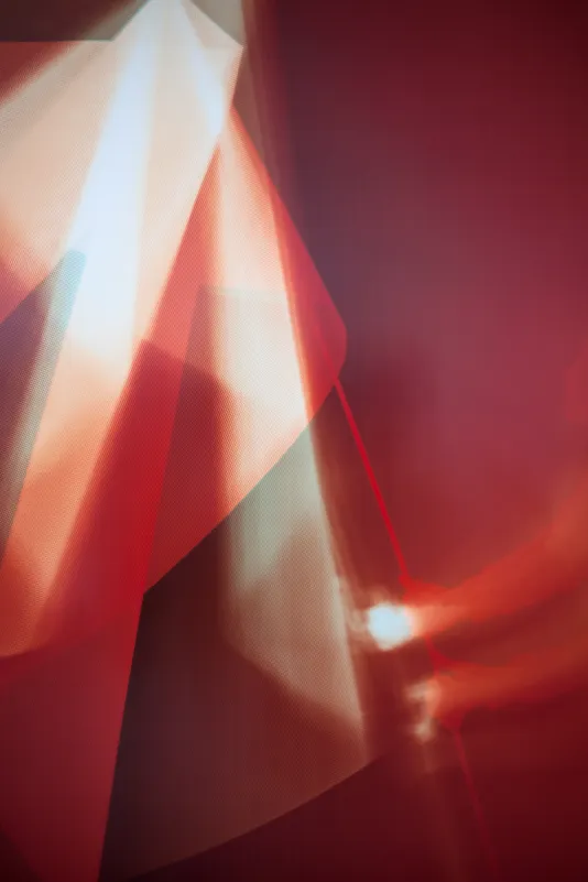 Detail view of a photogram print with angles and shapes in varying shades of orange, red, and white