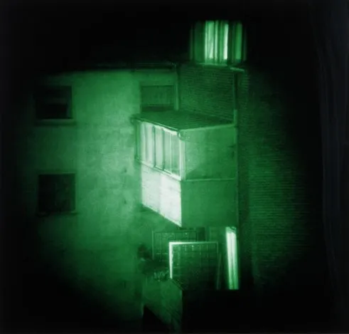 Night view of a covered balcony outside of a brick building, glowing in green light