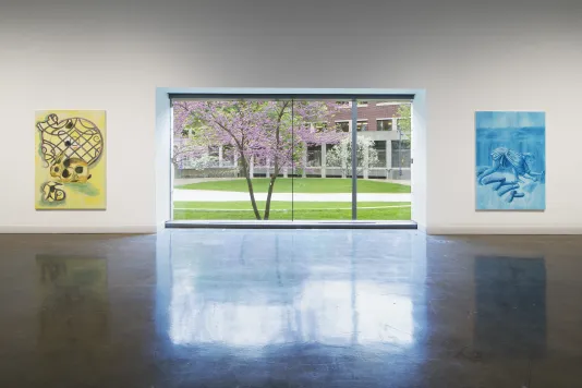 Two paintings hang at each side of a gallery window.