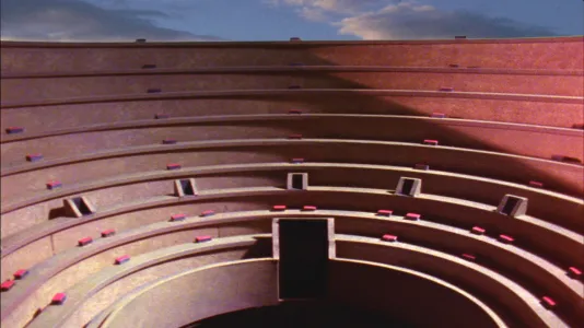 Video still of upper reaches of the convex seating of an open-air stadium. Blue sky and clouds visible at top of image.