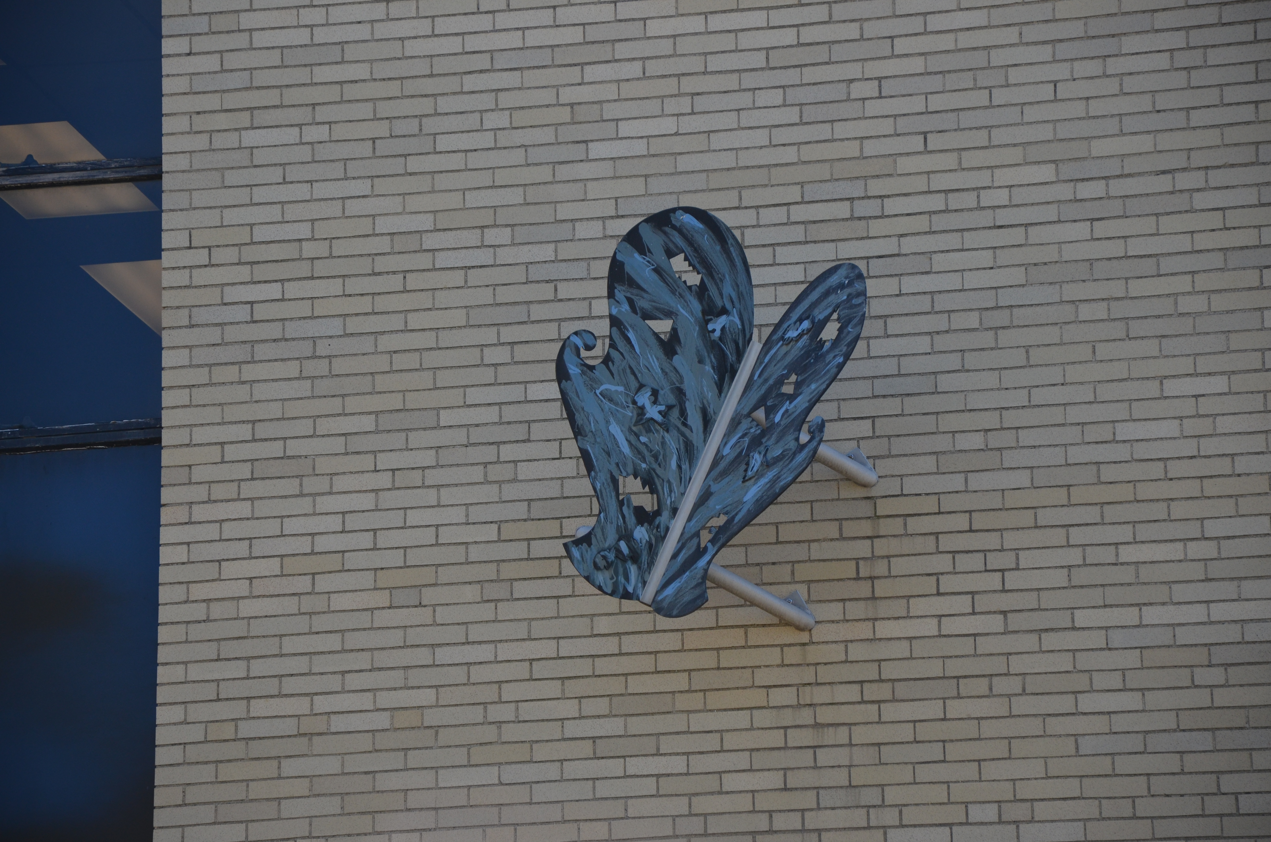 Steel butterfly mounted to a brick building wall.