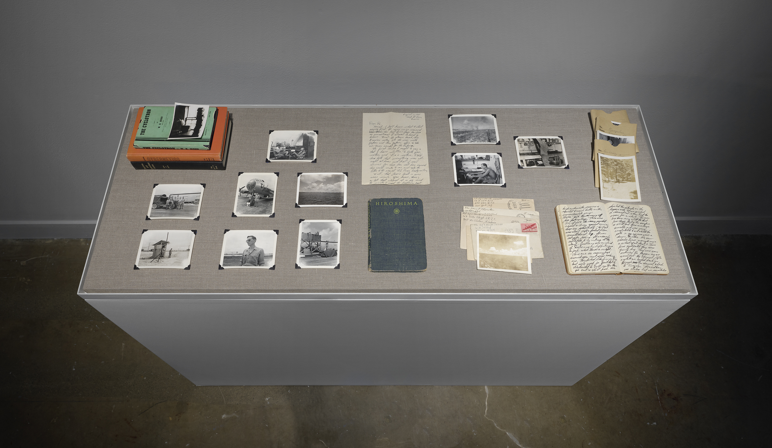 Books, postcards, letters, and photos from the Thornton family archives are arranged on a grey vitrine.