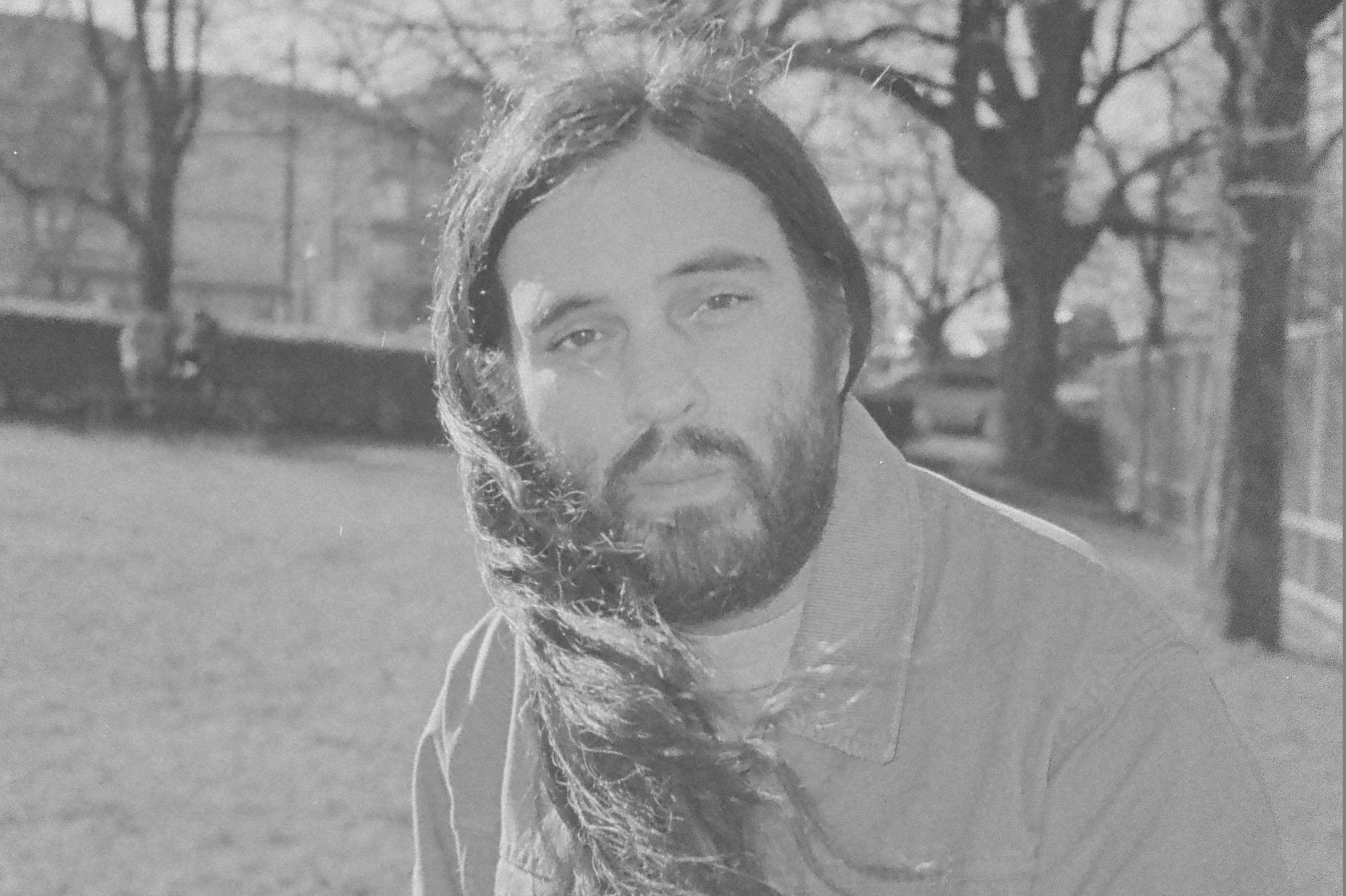 Black and white headshot of Raymond Boisjoly with trees and a field behind him.