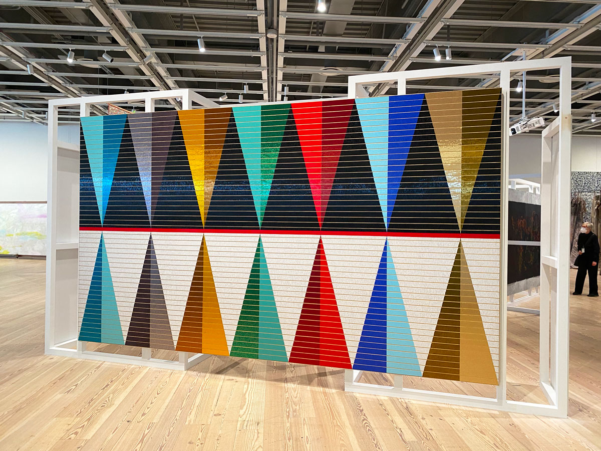A large installation in a gallery featuring reflecting triangle shapes on a large canvas.