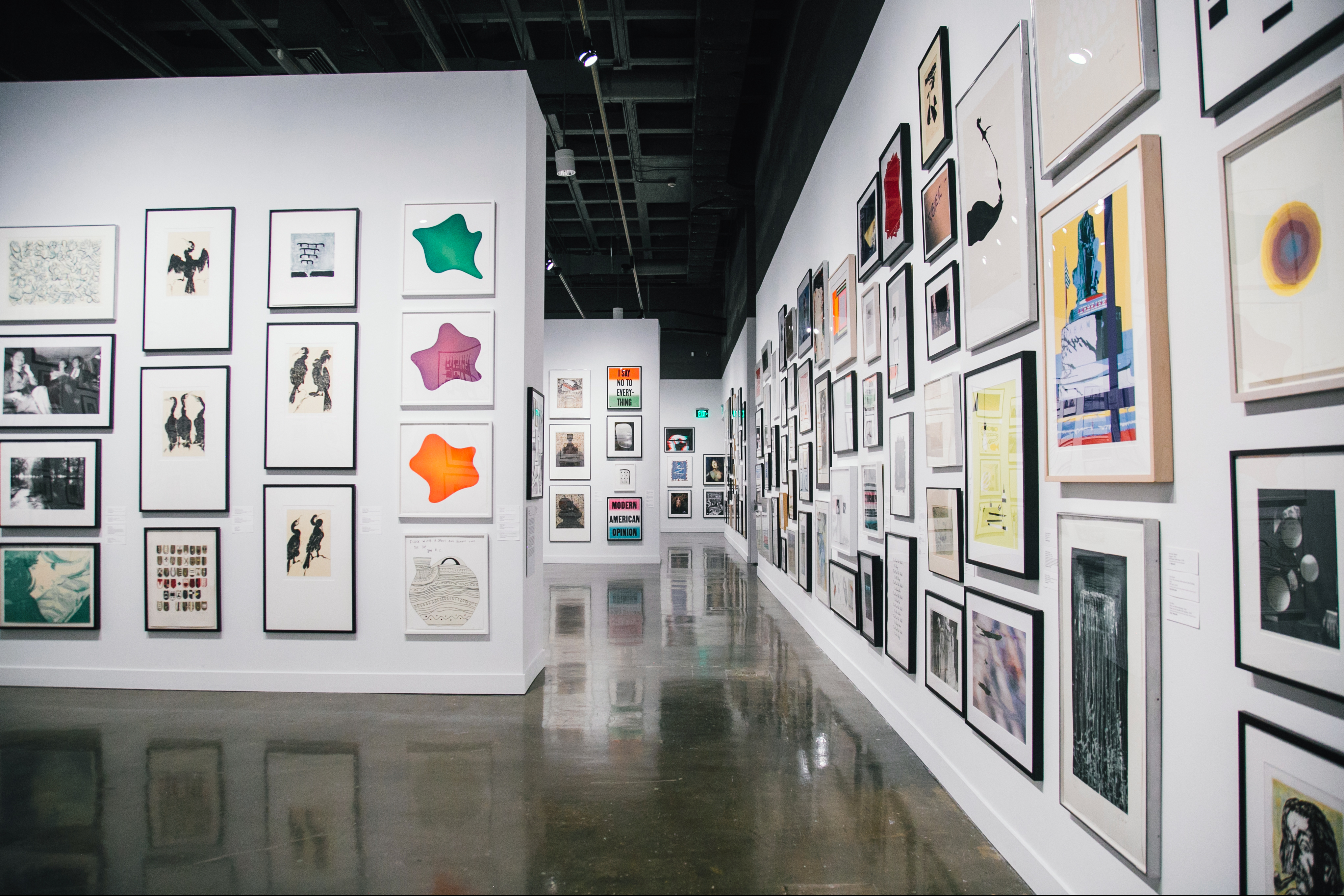 Installation view of framed pictures and prints lining multiple gallery walls