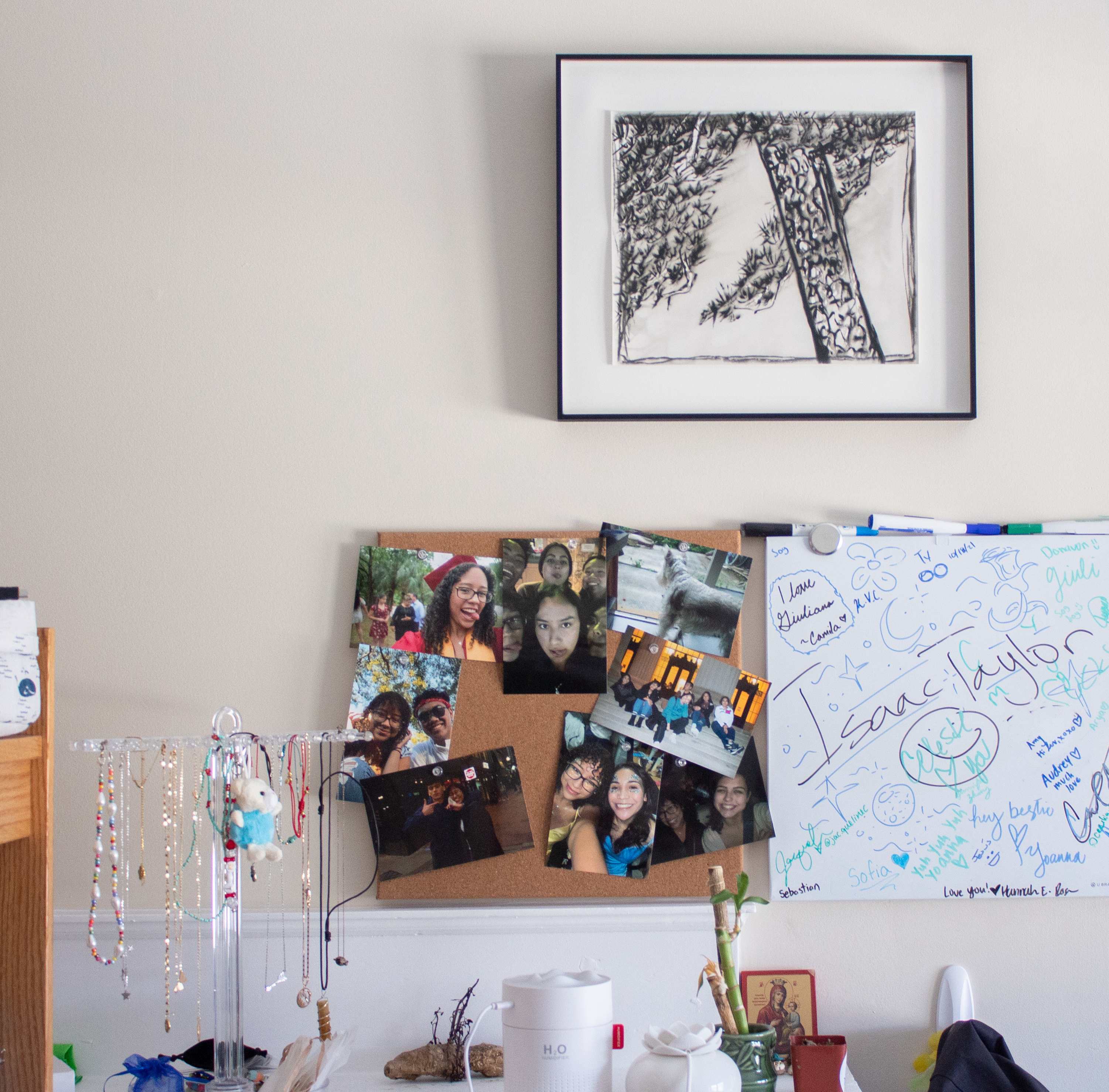 Photograph of a dorm wall with collage photographs, a black and white print and notes on the wall.