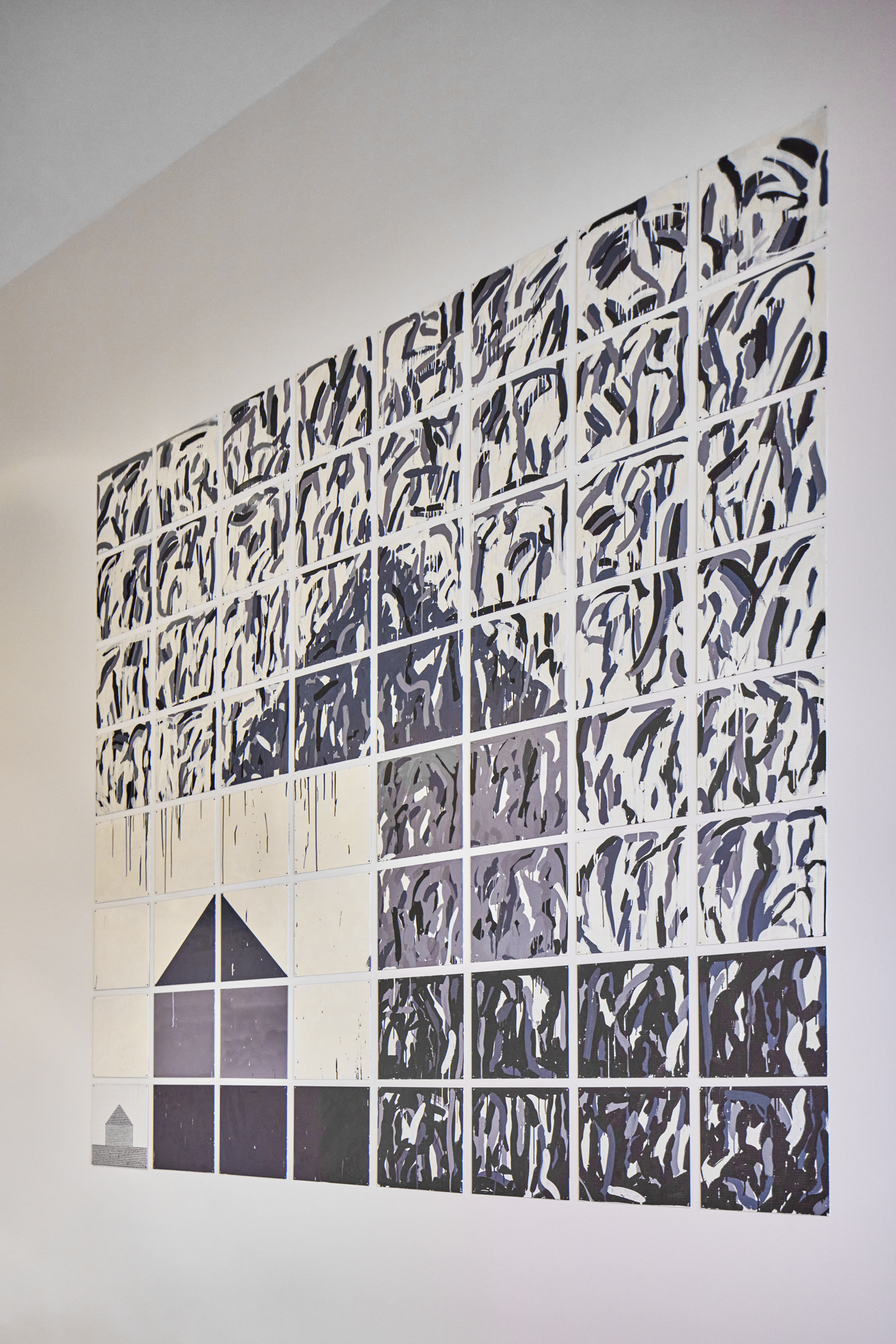 Rectangular artwork with tile like qualities and geometric shapes that resemble the shape of a house.