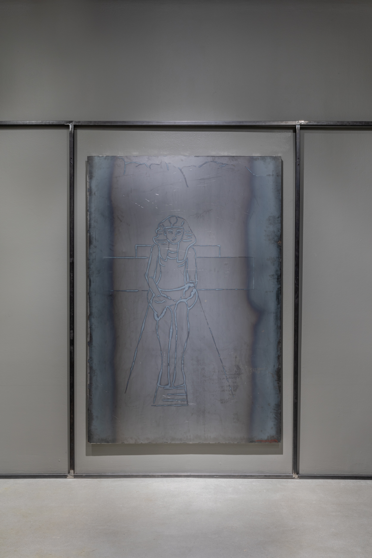 A large, vertical welded steel drawing hanging in the center of a wall in between two vertical steel bars and one horizontal bar above.