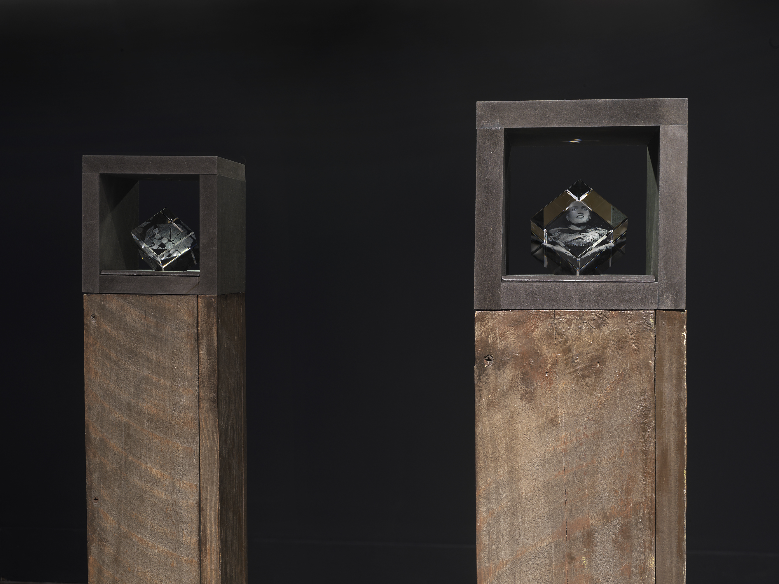 Small laser-cut glass cube sculptures nested inside the top section of brown pedestals.