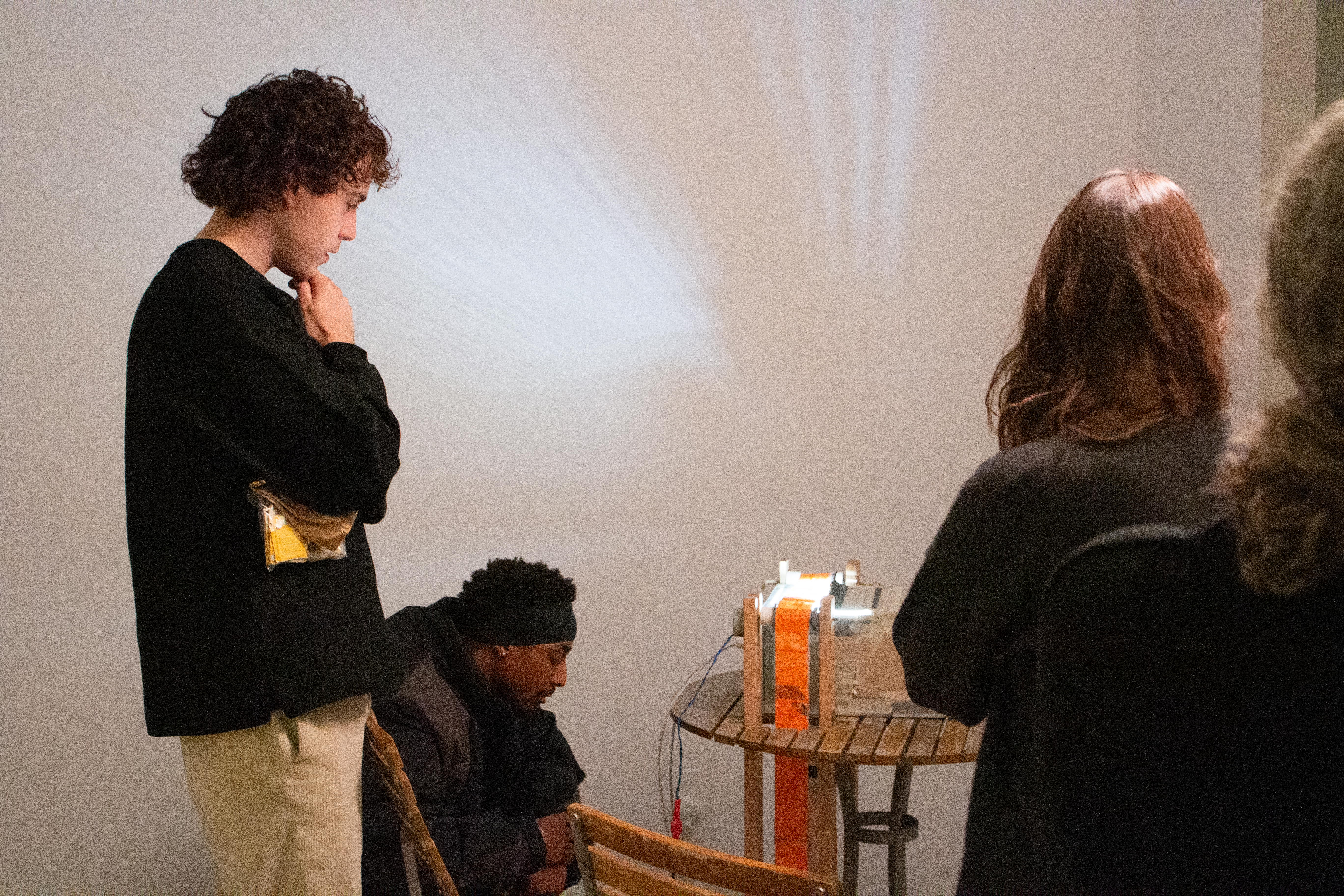 A group of students looking at the art piece titled Deltille-d Wall's Necessary Anachronism 2 by Sophie Friedman-Pappas