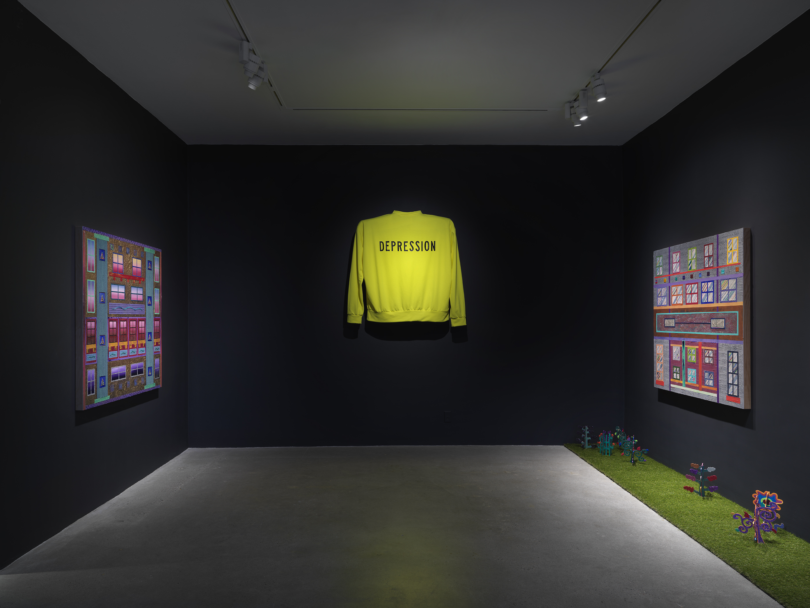 An art gallery with dim lighting showcases three artworks on the walls. In the  center, a bright neon yellow sweater with the word ‘Depression’ written across it is  displayed, elevated off the wall. On the left and right walls, two paintings with bright  geometric forms hang across from one another. A strip of astroturf on the floor lines the  right wall with small painted wooden plants emerging from it.