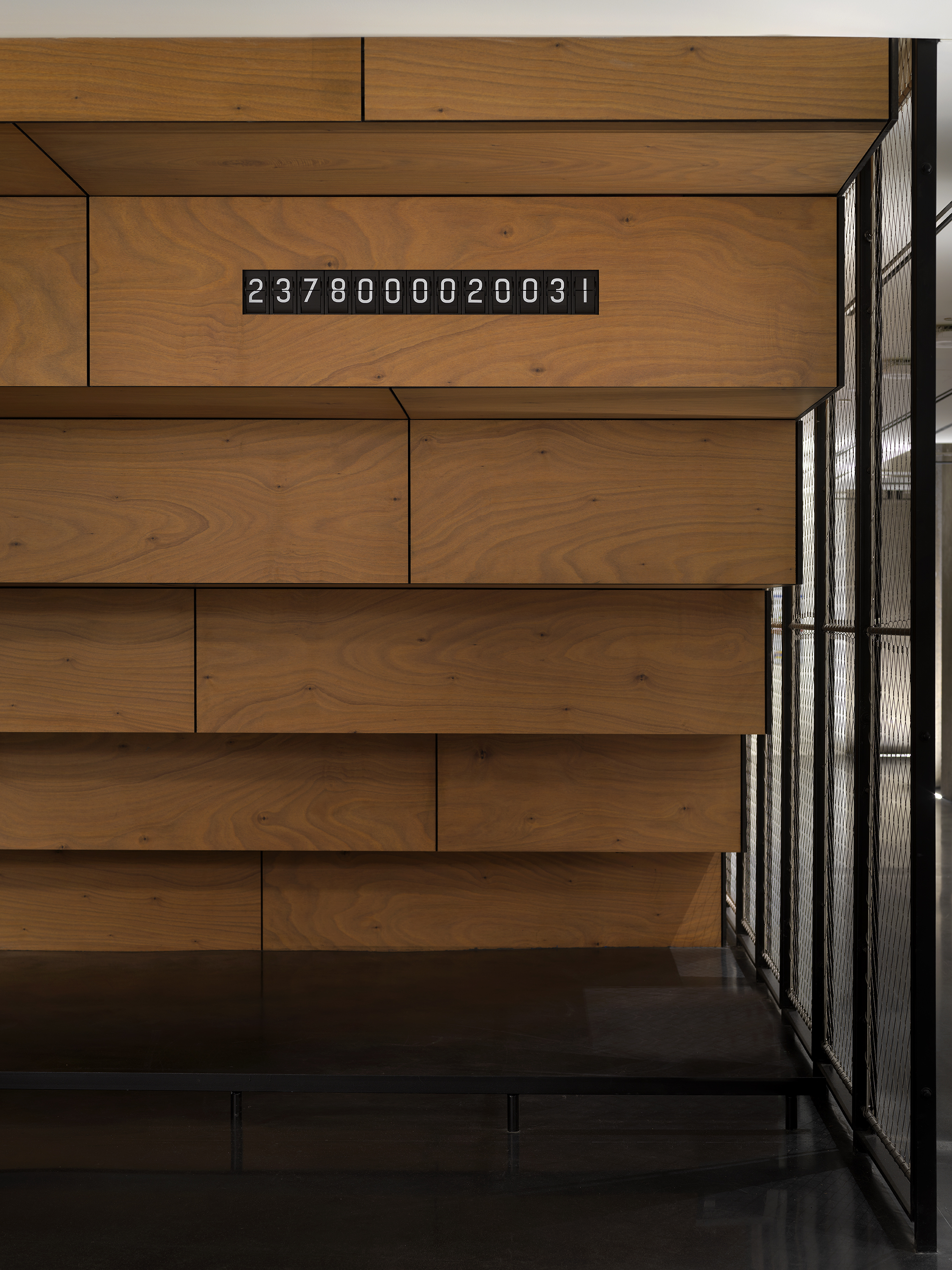 There is a black &quot;ticker clock&quot; with white numbers. The clock is placed on the underneath side of a wooden staircase.