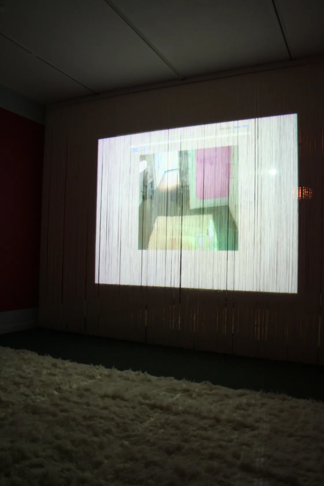 An image is projected onto a wall covered with fringe, distorting the picture.