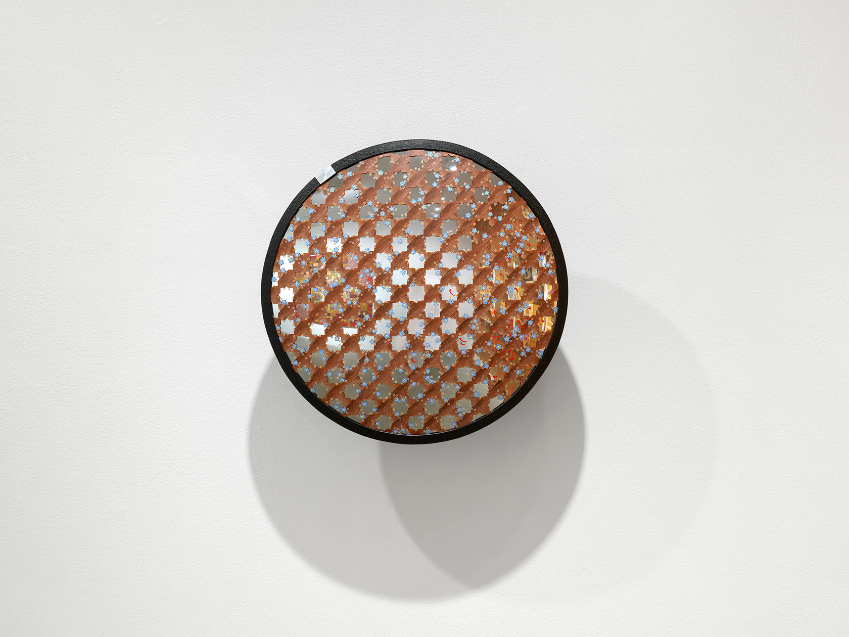 A round convex security mirror is covered by an interlocking brown star pattern created by intersecting notched lines. The pattern is adorned with delicately painted flowers.