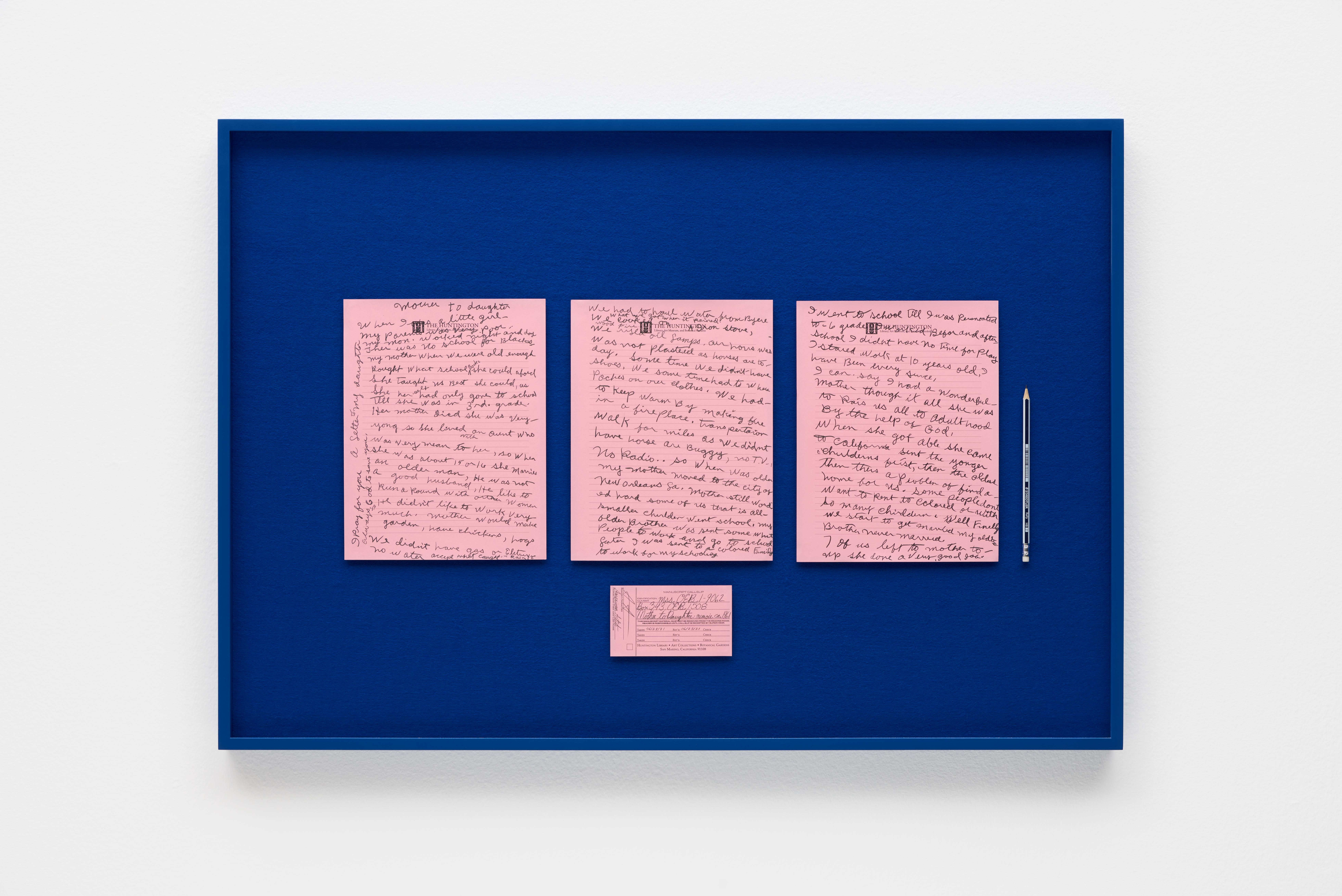 Three pink notecards with handwriting in black pen on top of a dark blue background inside of a black frame that hangs on a white wall.