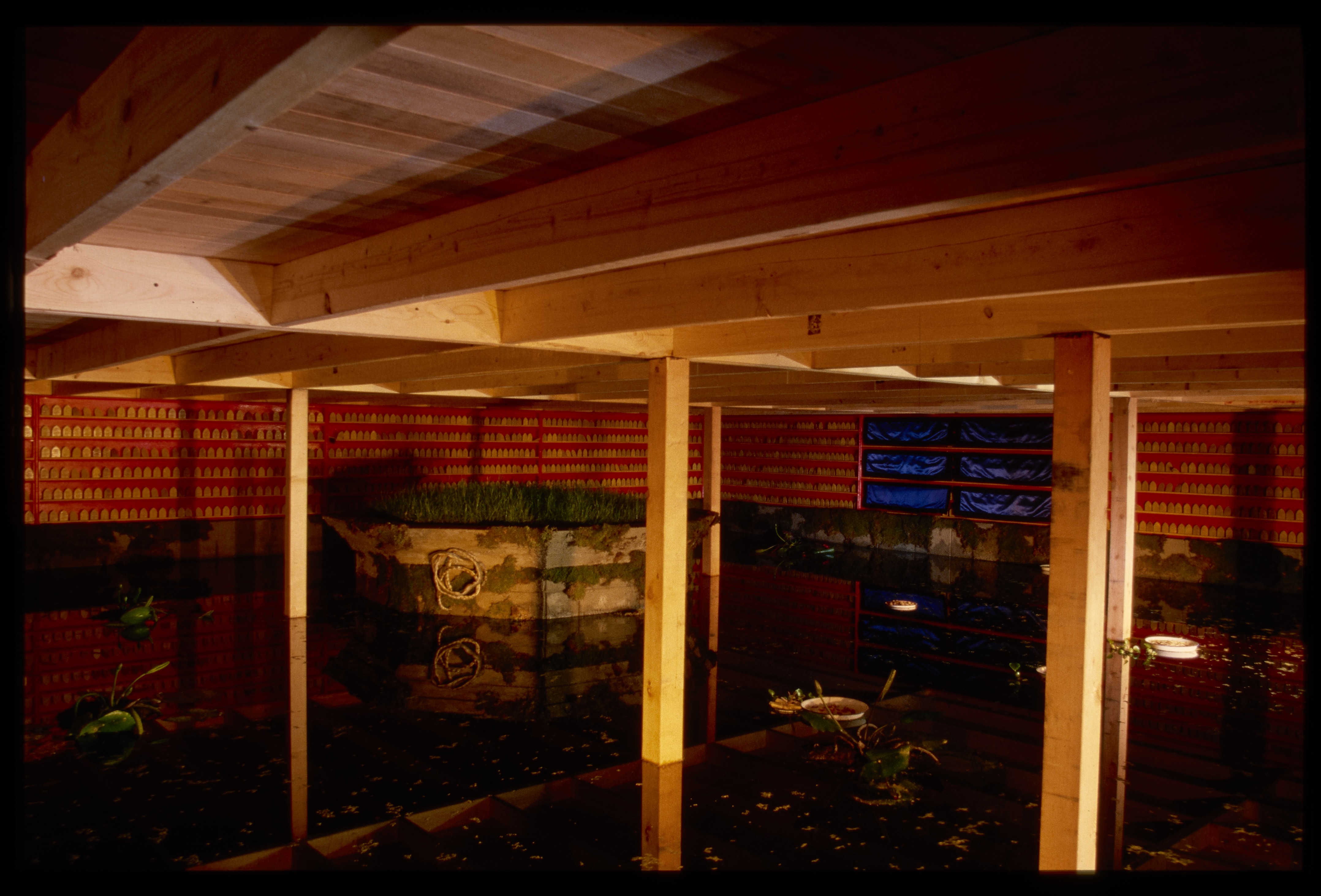 The gallery is split above and below. The top floor has a chair and two hanging lamps. The bottom is a warmly lit pond.