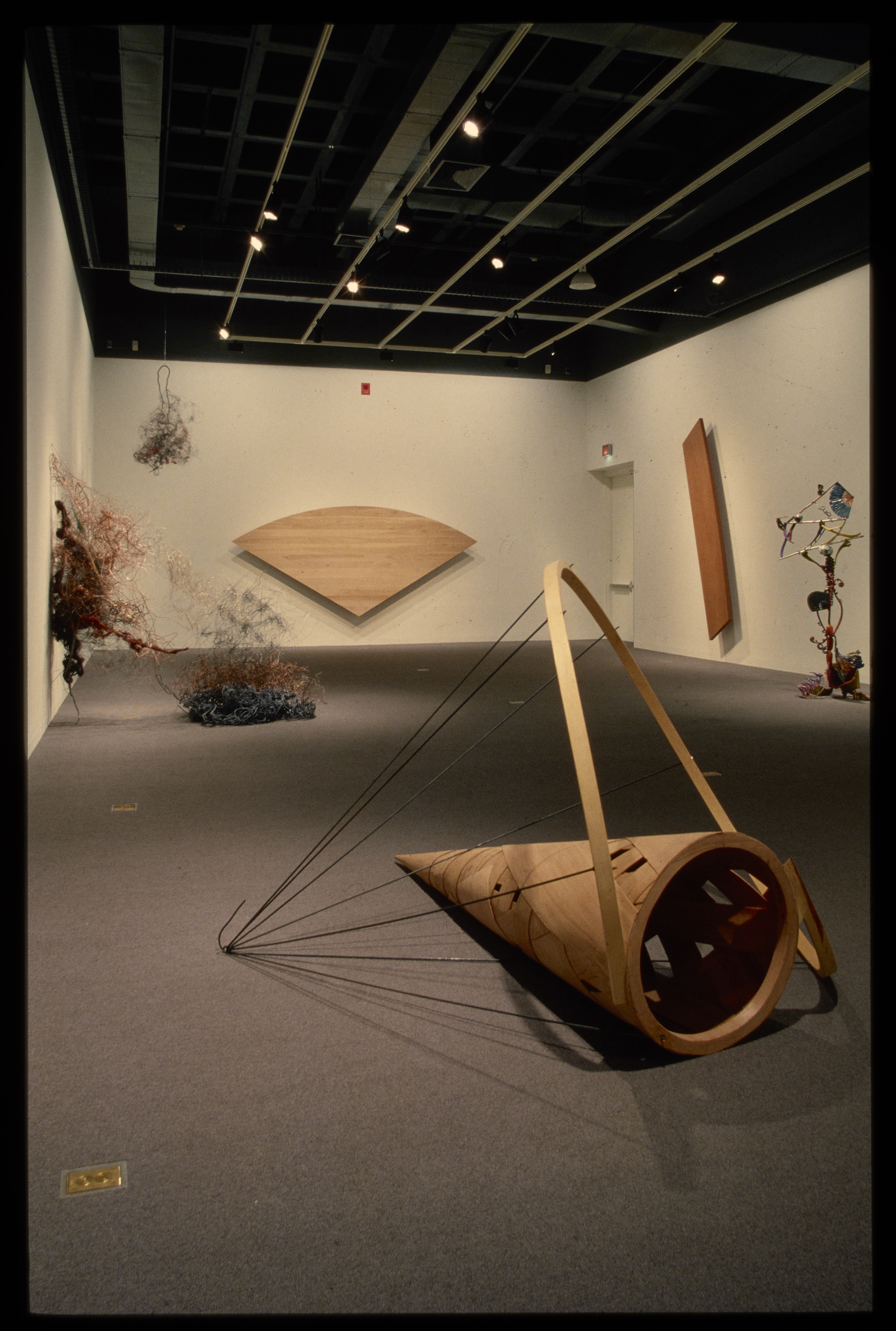 Organically shaped sculptures hang from the ceiling and walls. Each sculpture is spotlit, creating shadows on the floor.