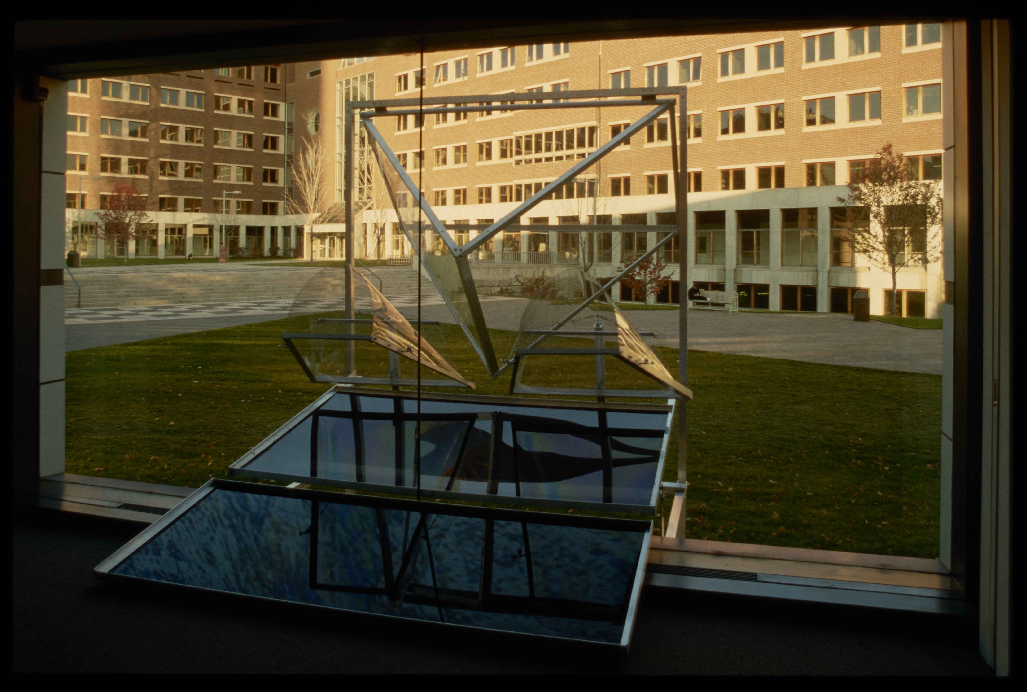 A sculpture made from window panes interacts with the window in the gallery. Panes create angled reflections of the outside.