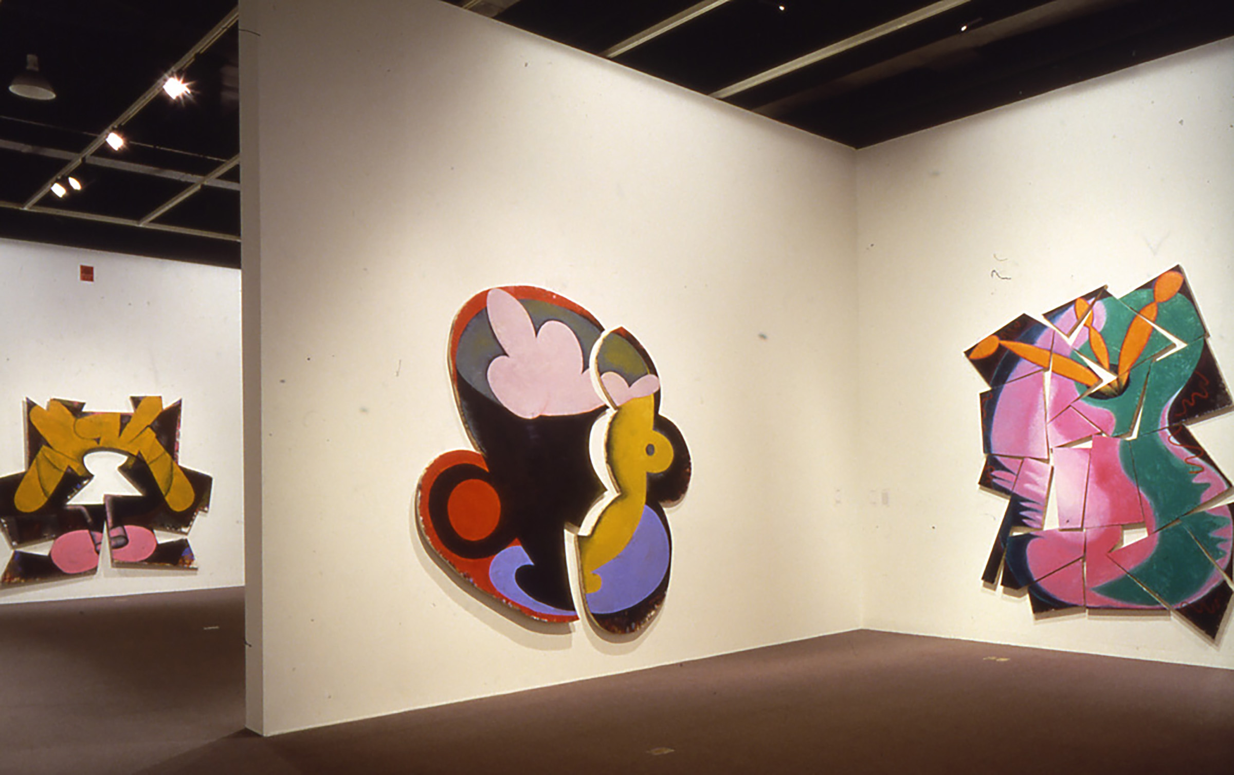 3 unique shaped vivid paintings hung on walls, 1 painting is made of 2 canvases to look like a broken coffee cup on a saucer.