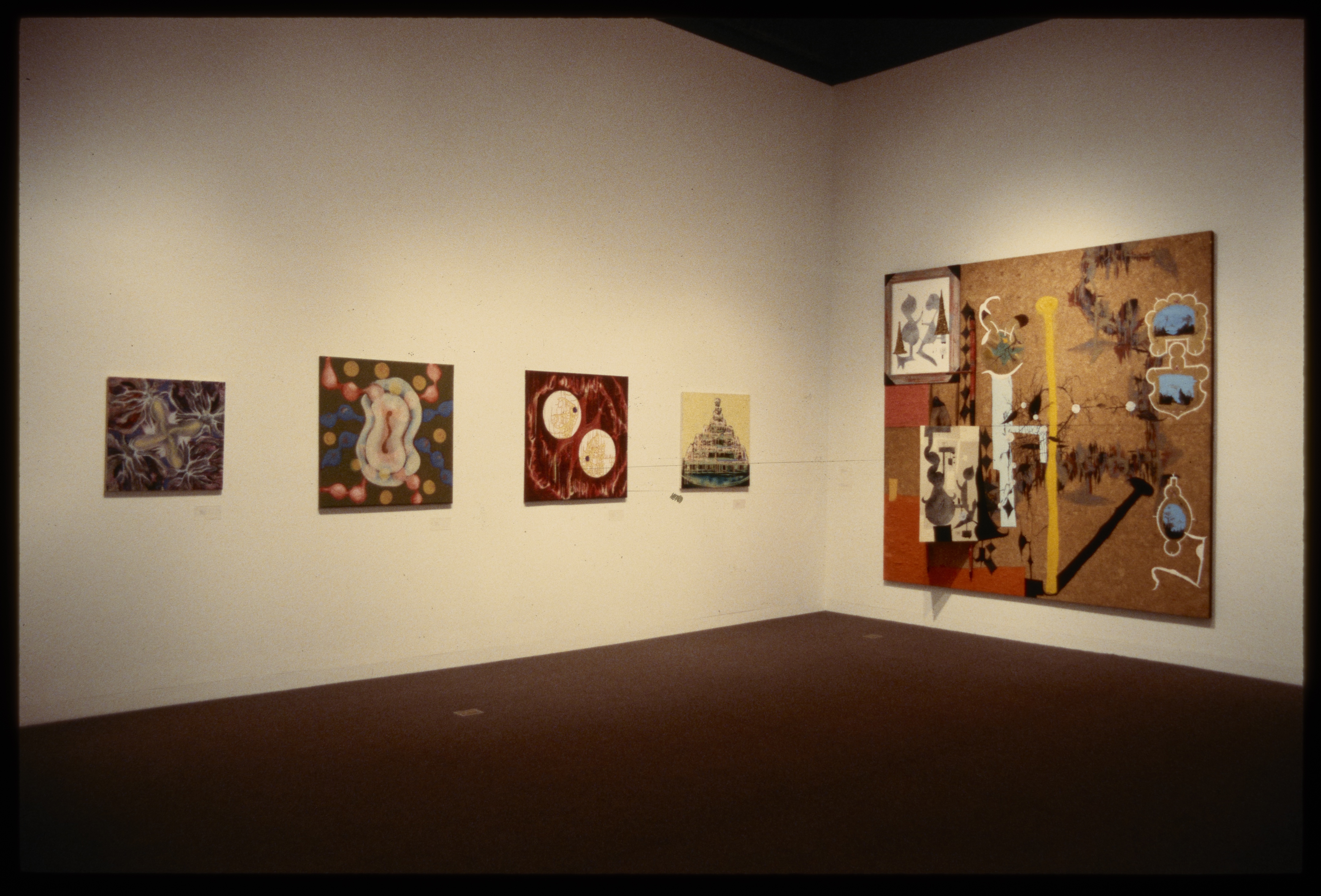 Four canvases with abstract colorful configurations are hung adjacent to large abstract colorful canvas.