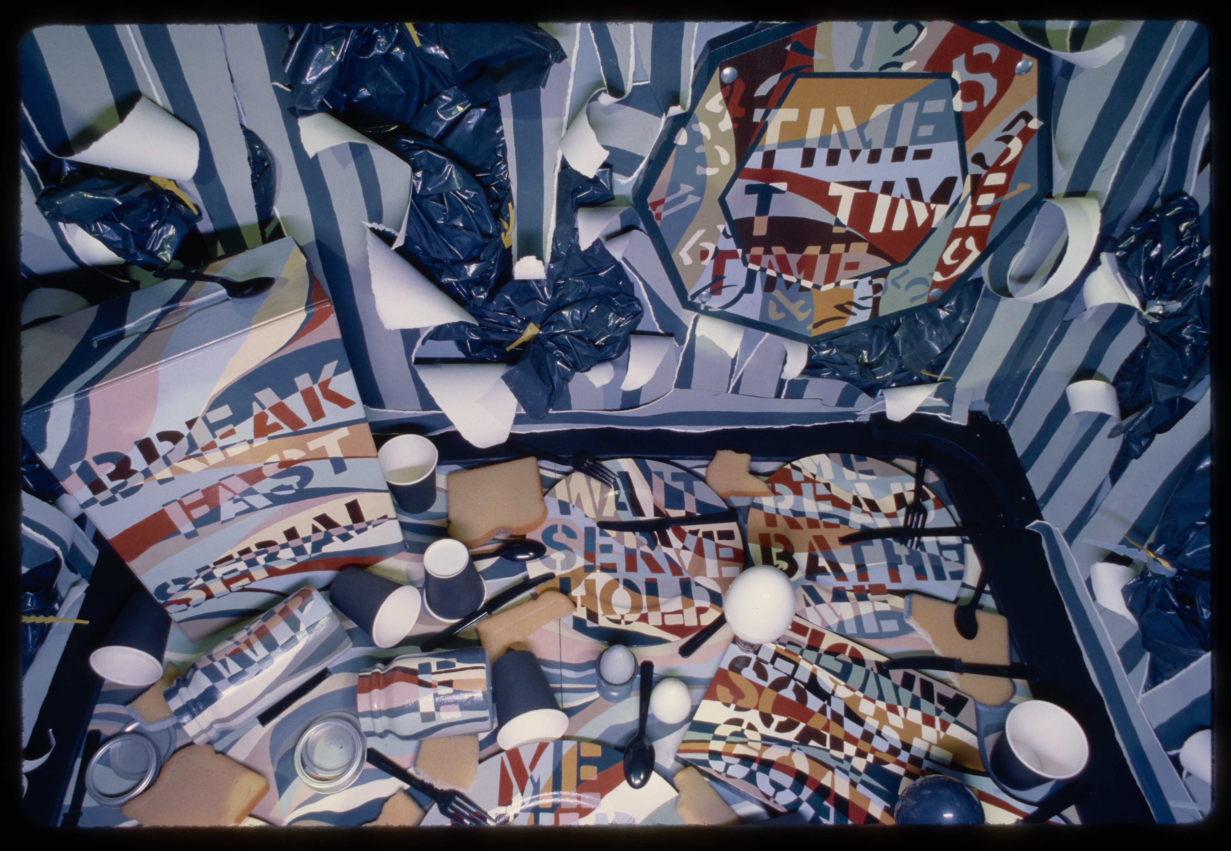 Inside view of a dollhouse sculpture showing a home in disarray. Words are incorporated such as HOLD ME and SERVE ME.