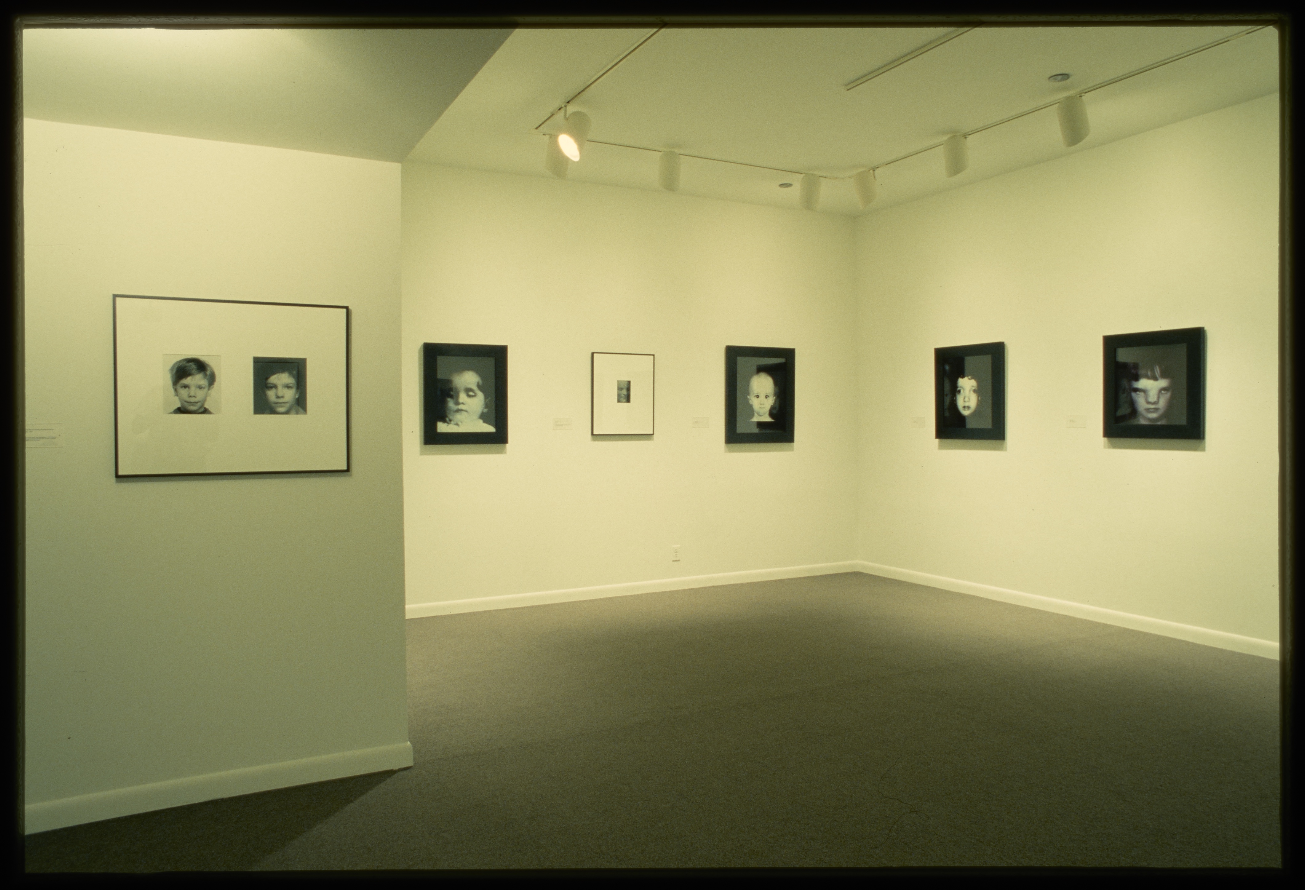 A row of black and white photographed portraits hang at eye level across the gallery wall.