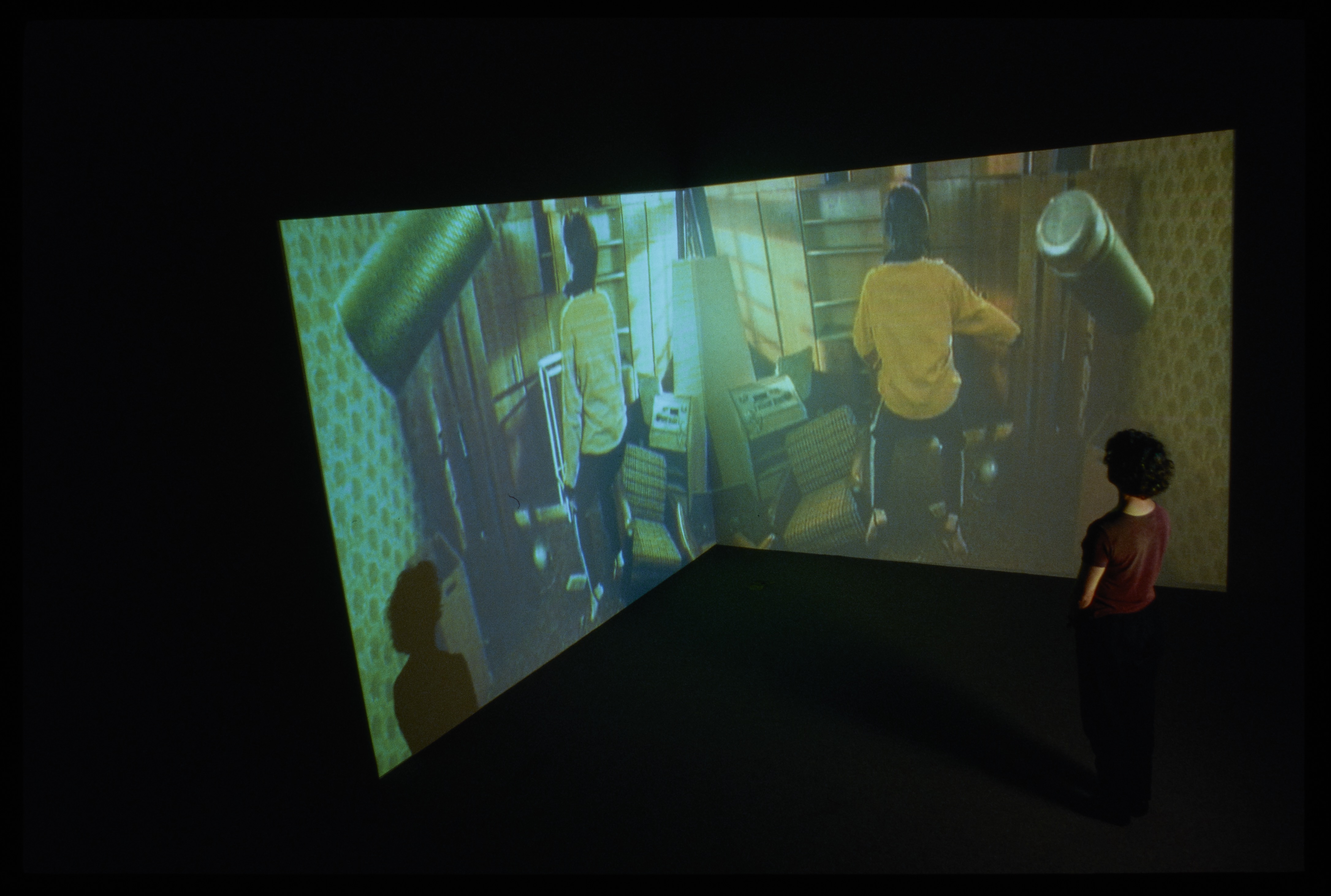 In a dark gallery, 2 screens in a corner.