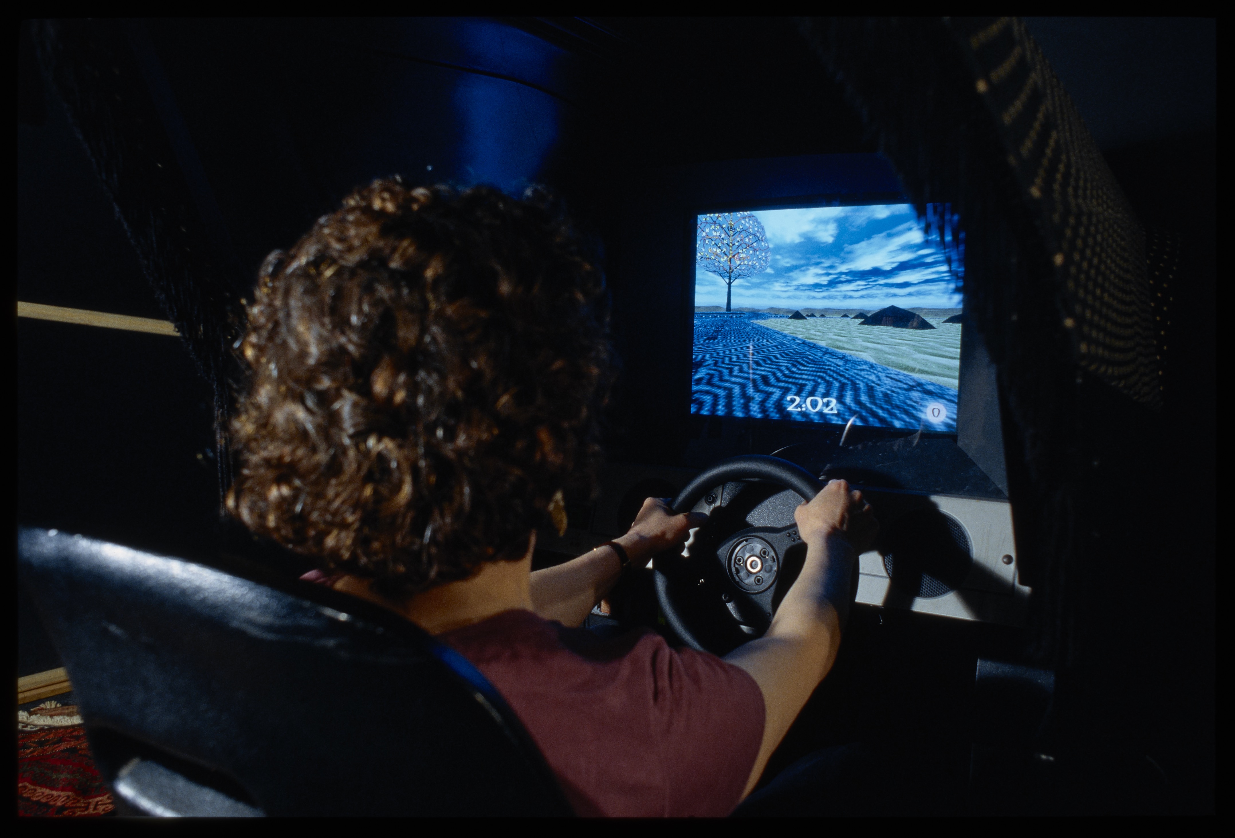 Close up of the woman playing the video game with a steering wheel.