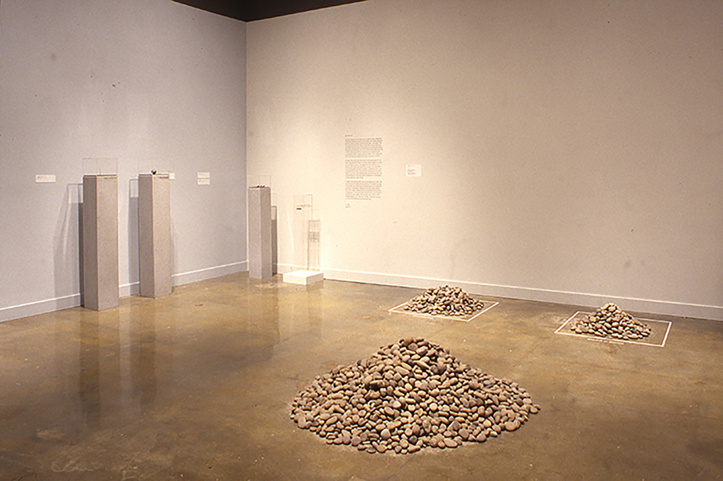 Three piles of sand colored stone lie opposite thin gray pedestals
