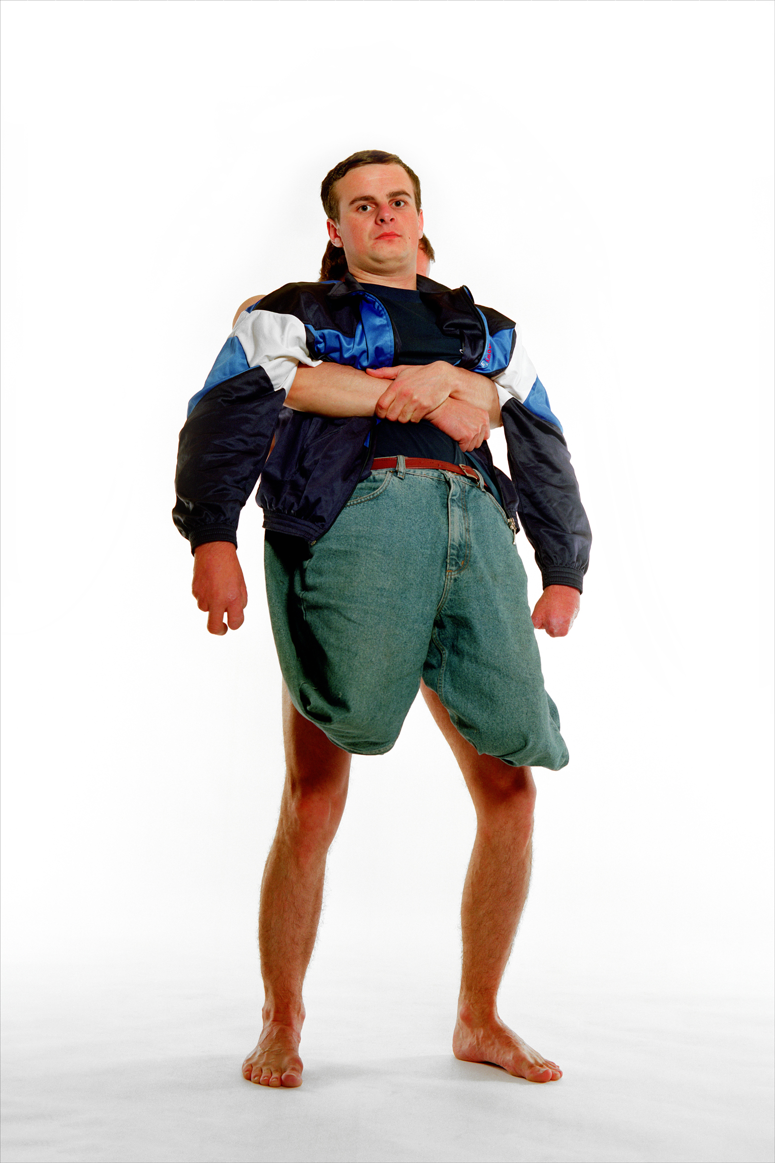 Able bodied man hugs arms around a man without legs, holding him up from behind