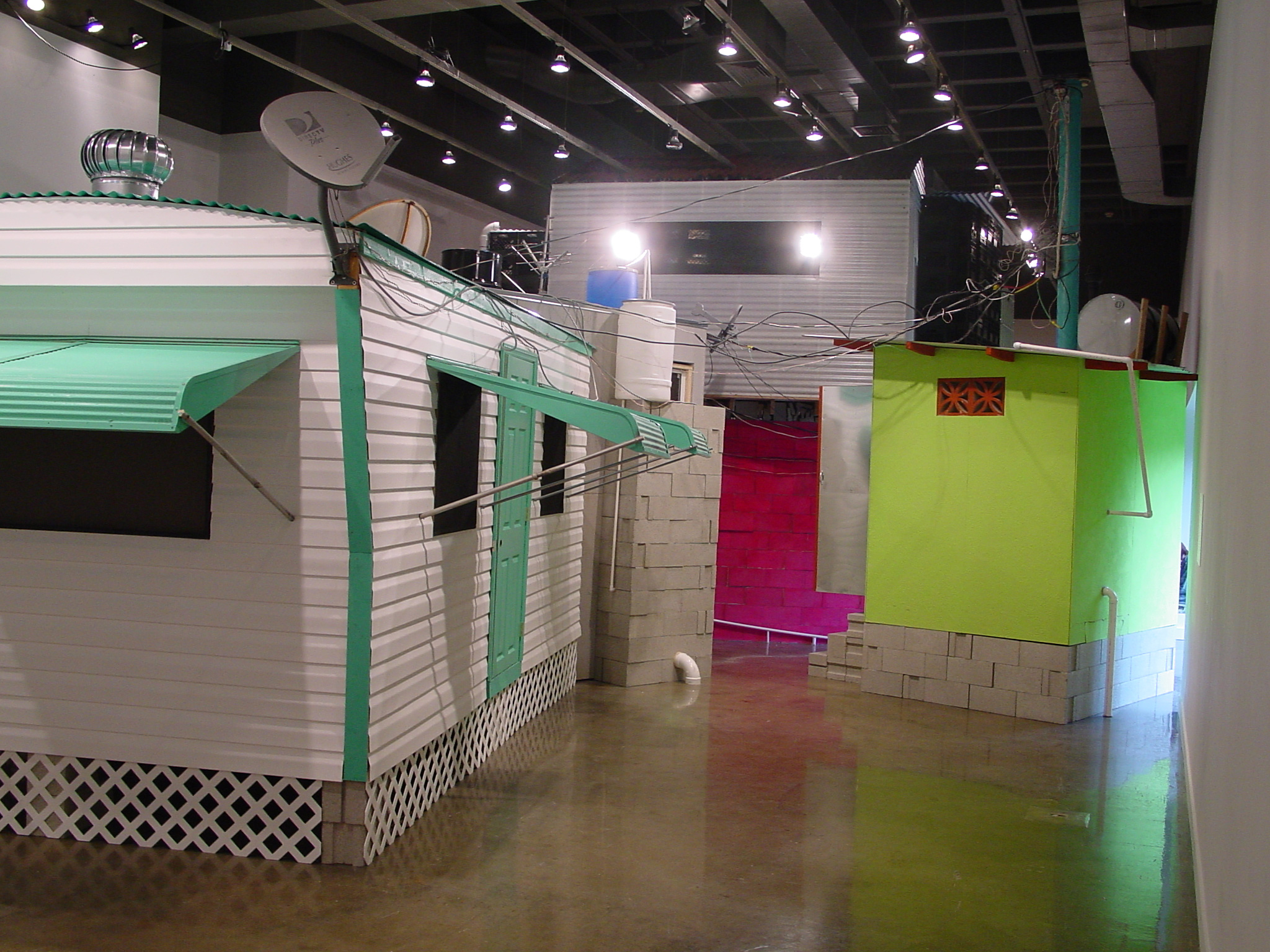 Multiple built structures including a bright green building to the right and a white house with turquoise accents to the left