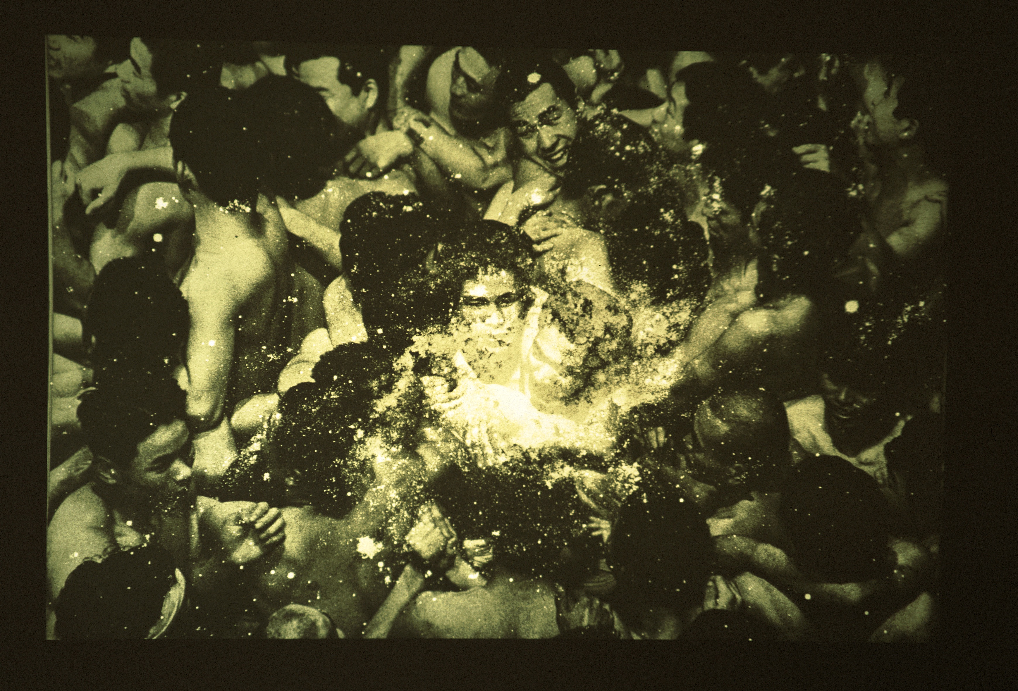 An old image showing people closely packed together, with two figures at the center illuminated by another image overlaid.