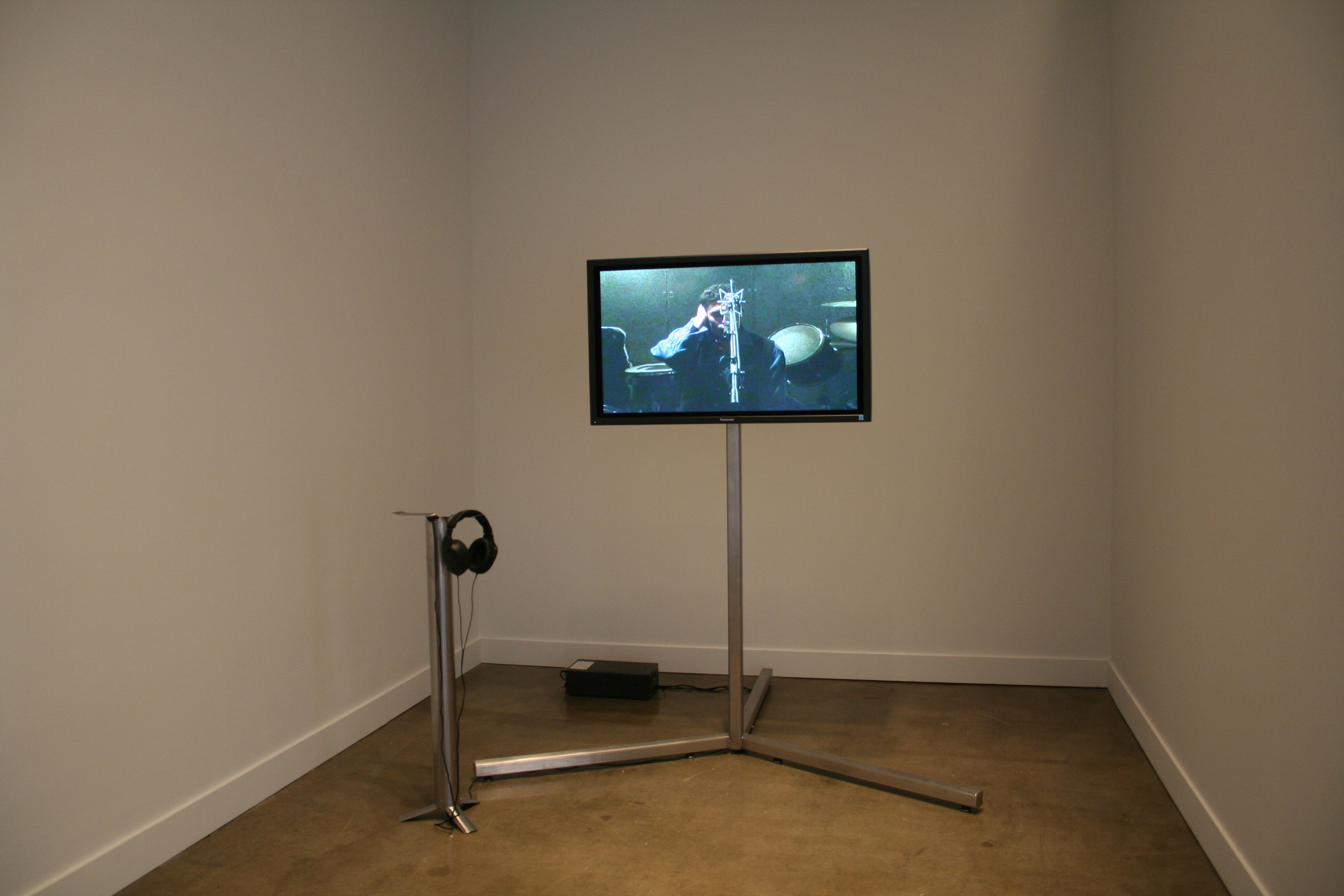 Television monitor on a stand with a smaller stand for headphones