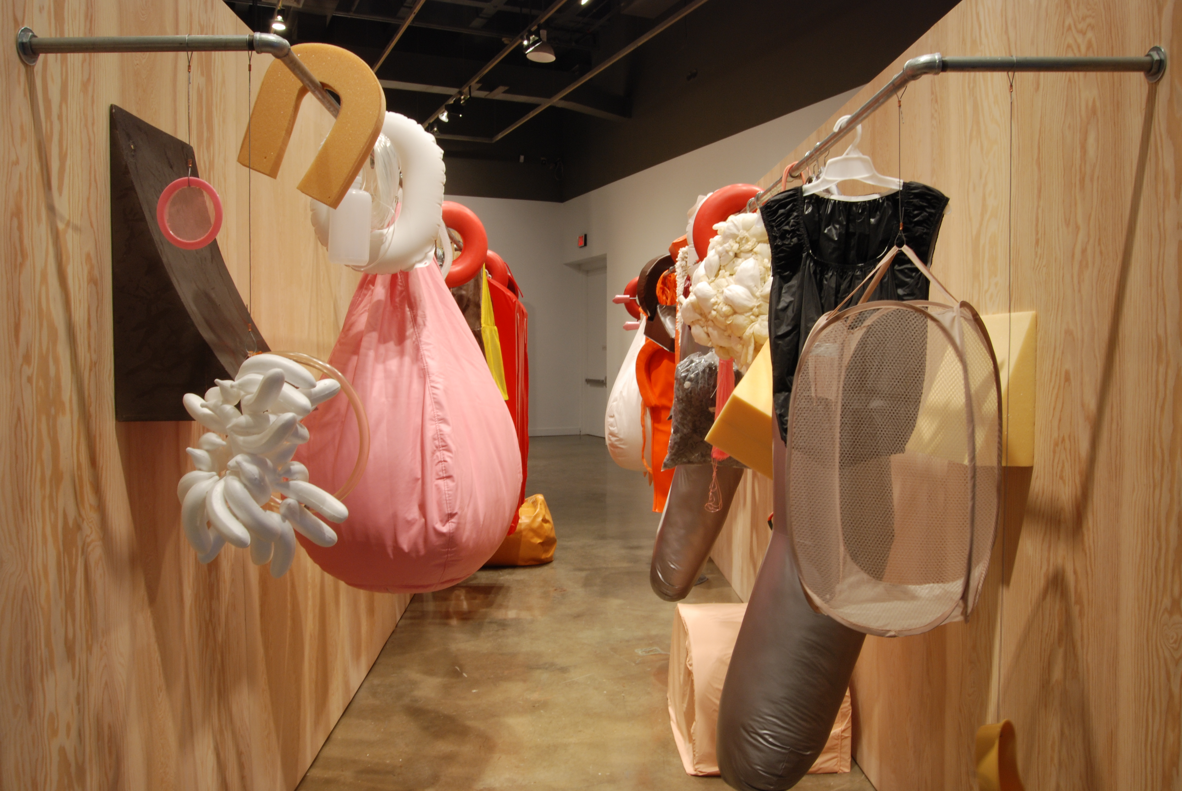 A wood paneled space with metal racks holding mostly white, black, and orange objects like theatrical props