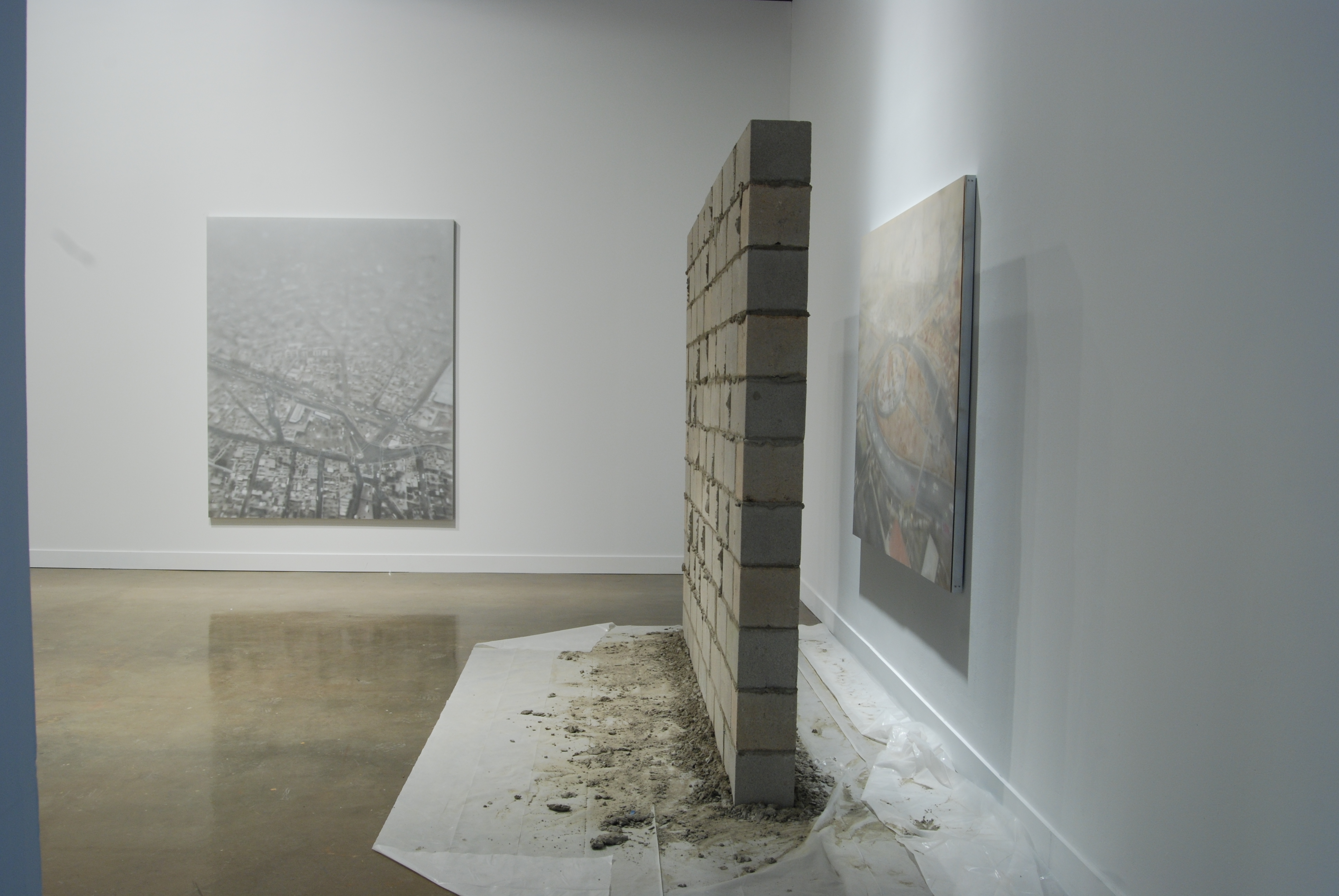 Two large photos on the walls, and a cement brick wall a few feet wide and standing on an acrylic sheet with cement dust