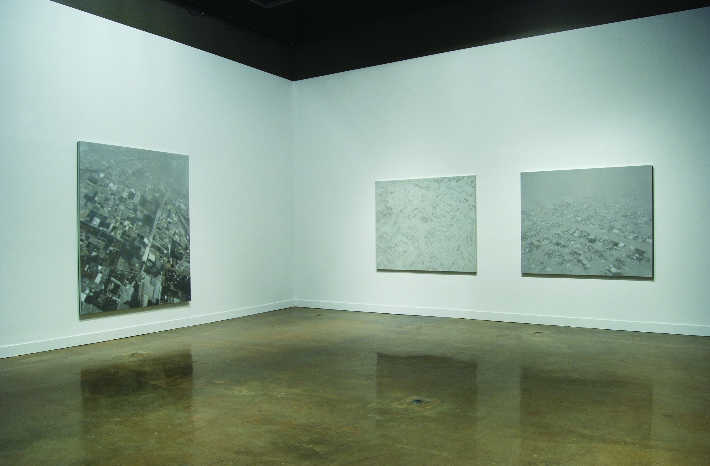 A large black and white aerial view of a city on one wall, and two gray, abstract panels on the other wall
