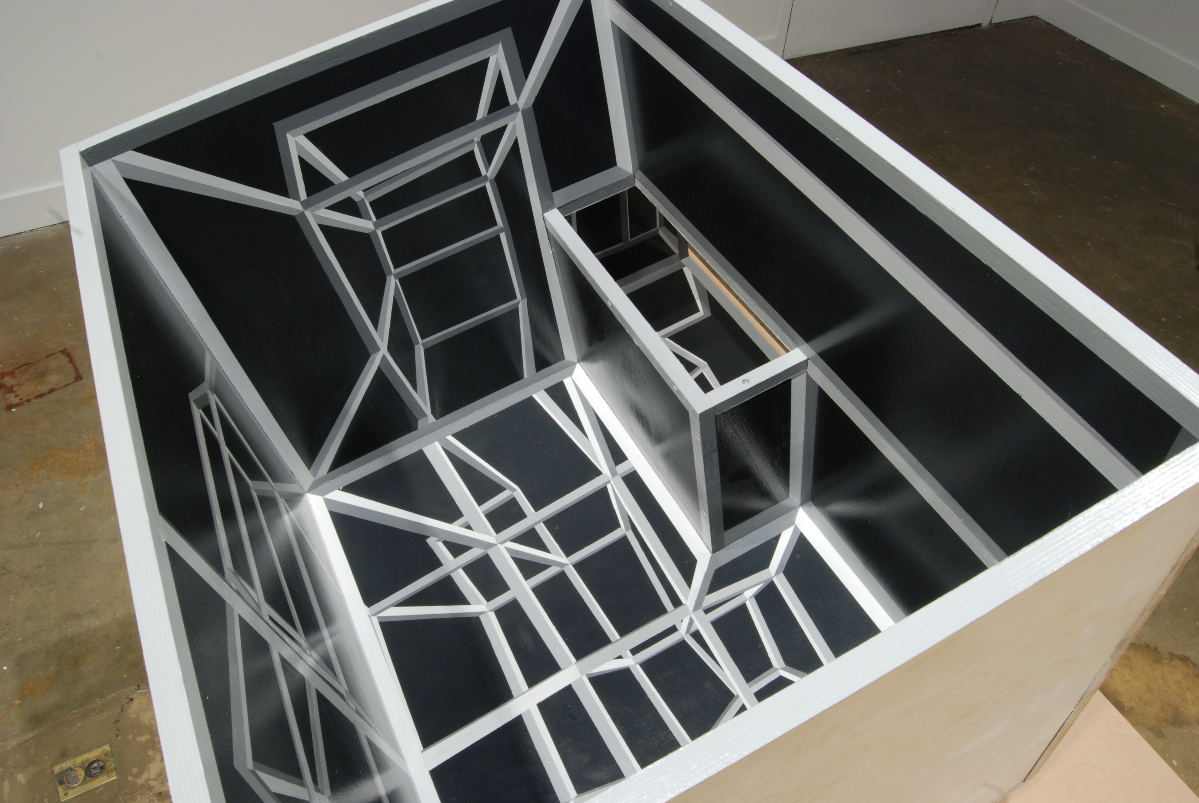 Gray, white and black geometric drawing and rectangular intrusion create optical dimension within a white box.