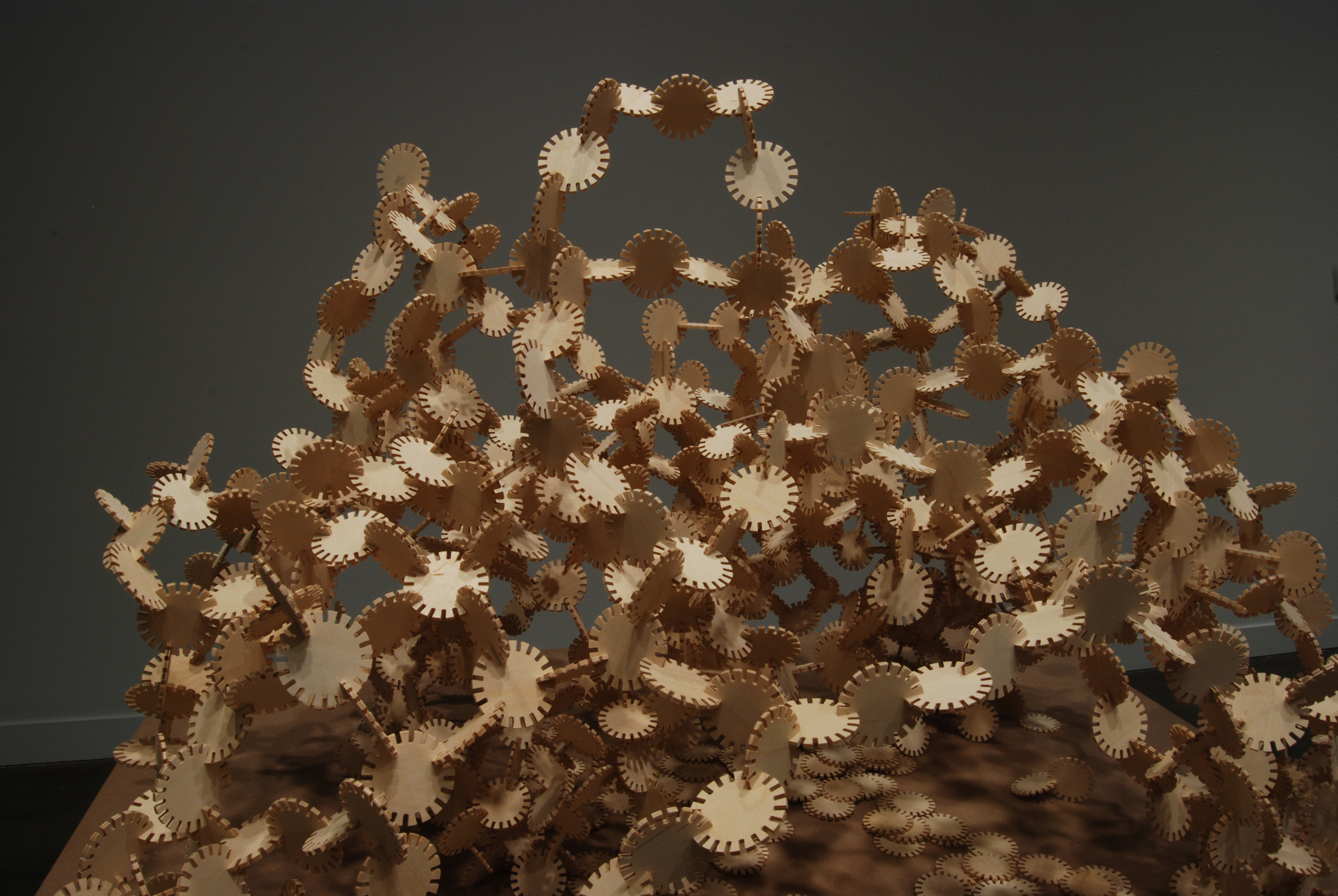 Tan-color, small round discs with cut-out notches around edge connect to form an airy, dome-shape mound.