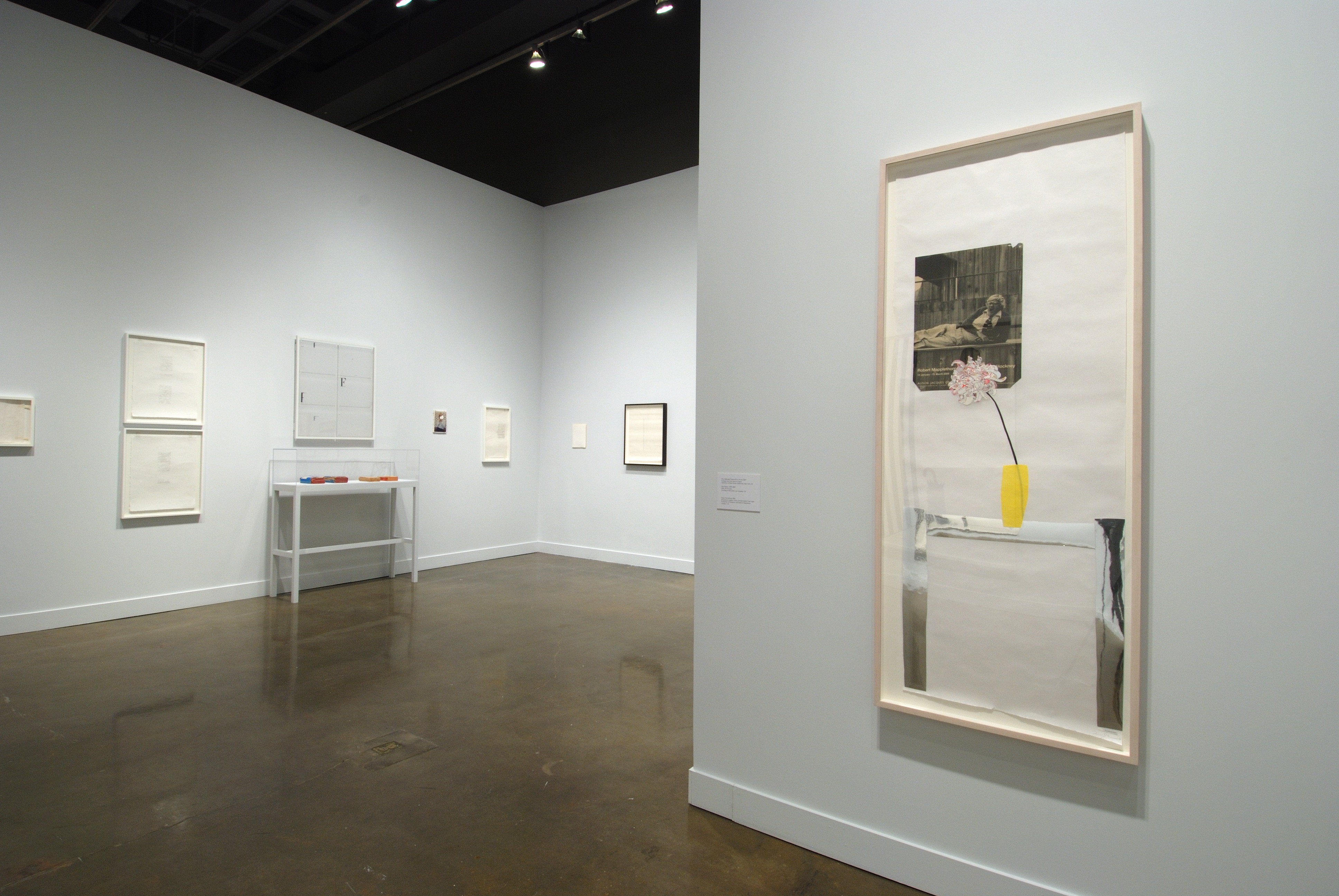 Installation view of the List Center gallery. In the foreground is a framed collage of a chair with a yellow vase and and a black and white photograph.